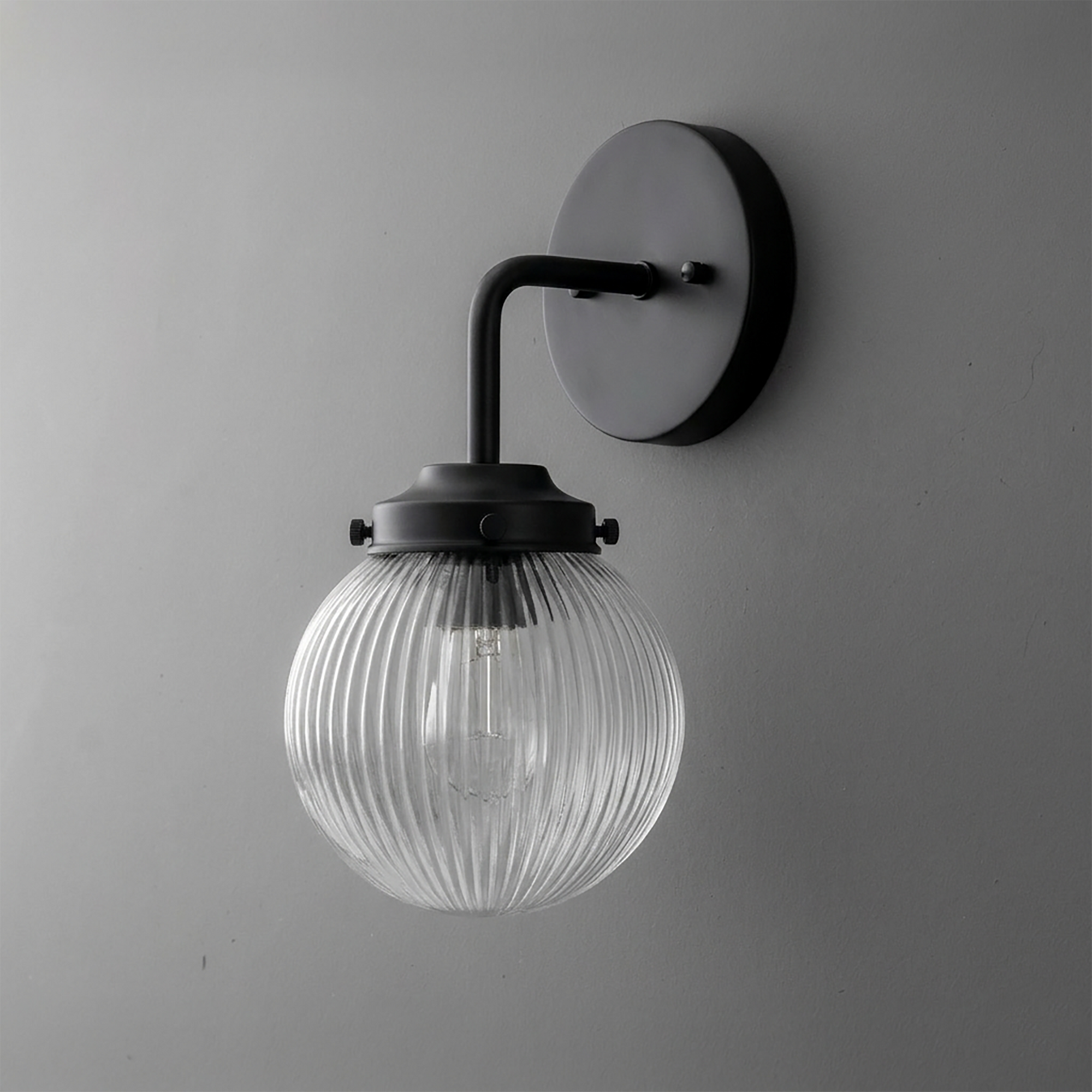 Black metal wall sconce with ribbed clear glass globe shade and single bulb design. - SCONCE MODEL NO. 6857