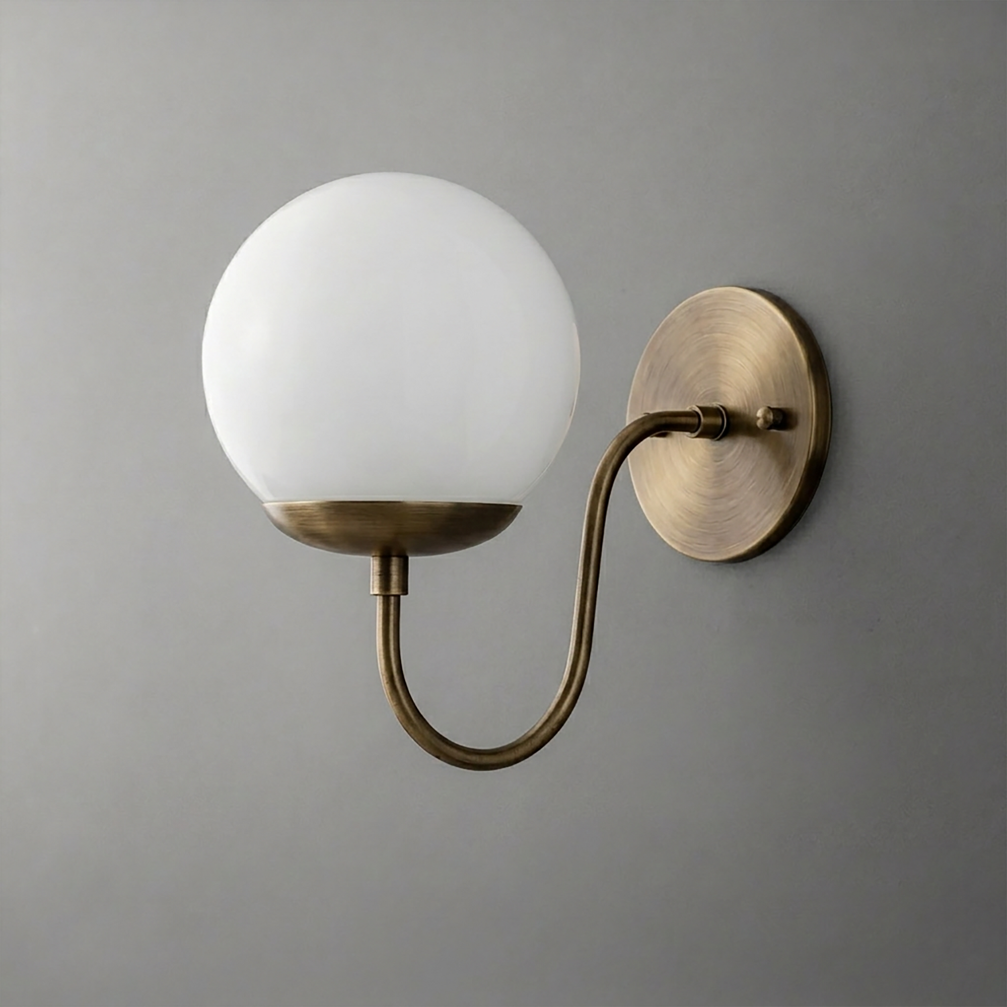 Wall sconce with a round white glass globe shade and curved antique brass arm and base plate. - SCONCE MODEL NO. 3849