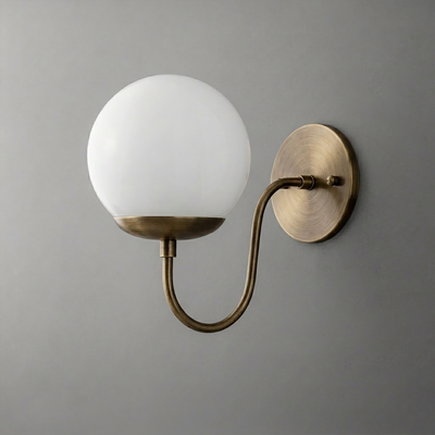 Wall sconce with a round white glass globe shade and curved antique brass arm and base plate. - SCONCE MODEL NO. 3849