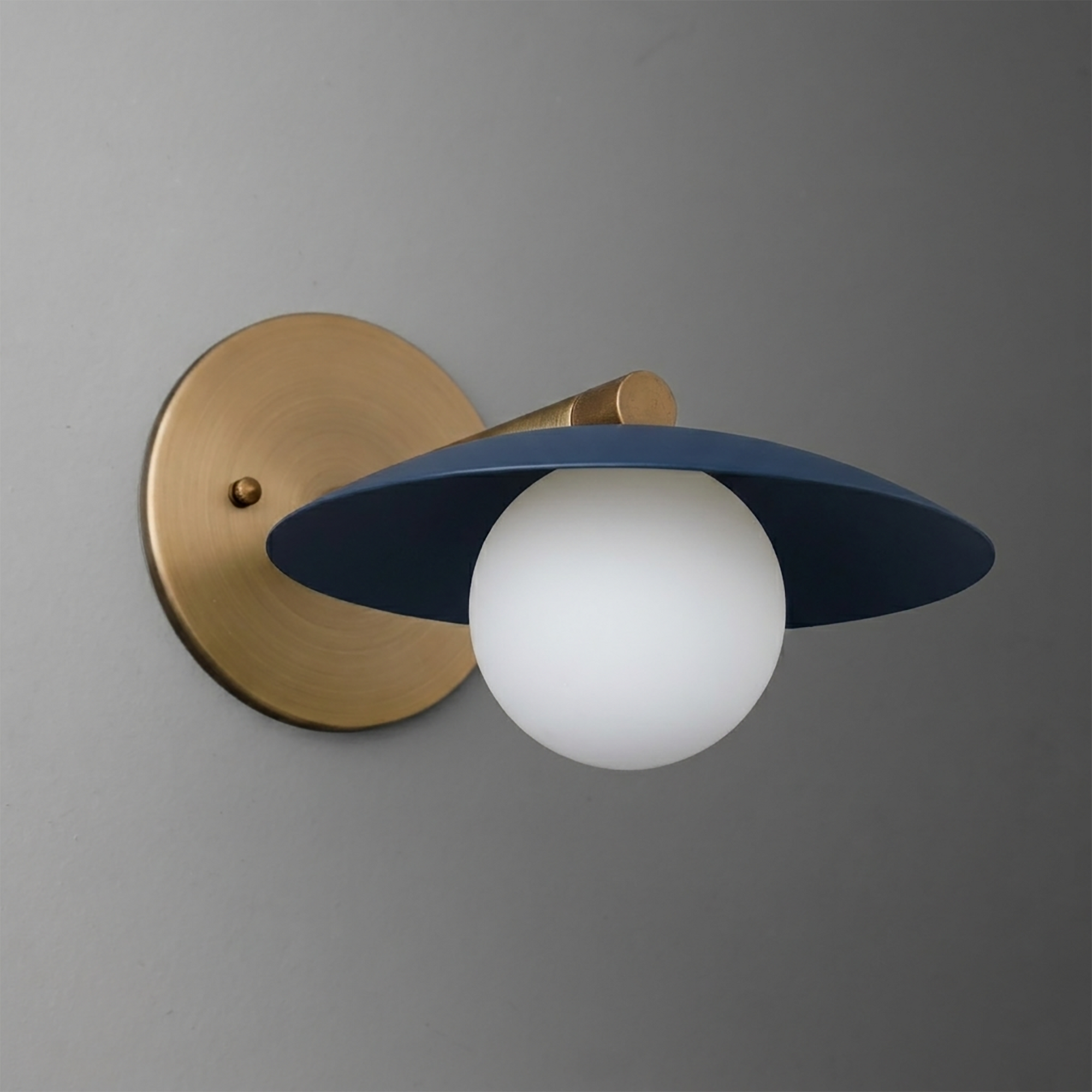 Wall-mounted sconce with brushed brass base and arm, featuring a matte navy blue wide flat shade and a frosted white glass. - SCONCE MODEL NO. 9872