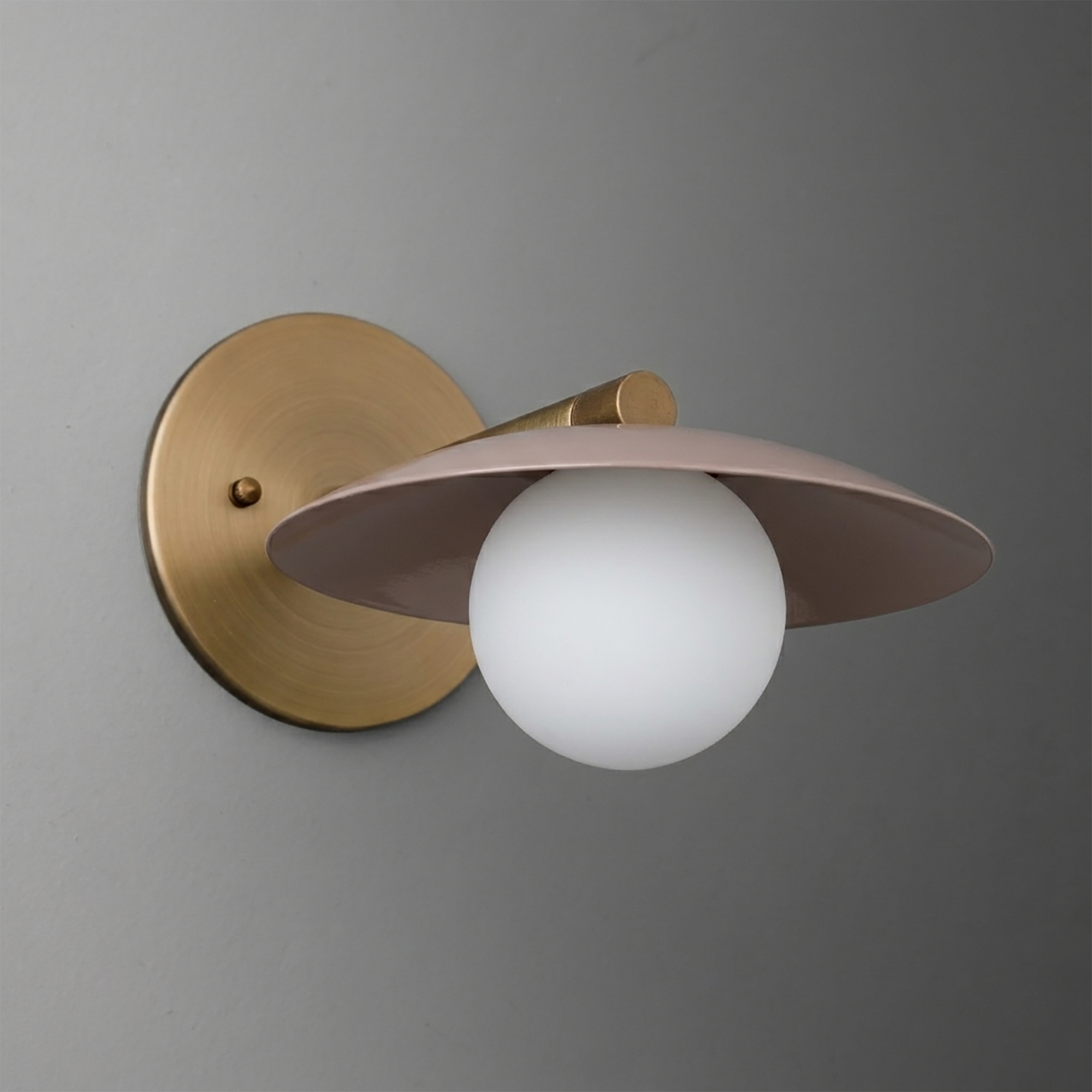 Wall-mounted sconce with matte brass round base, thin angled taupe metal shade, and white globe bulb. - SCONCE MODEL NO. 9872