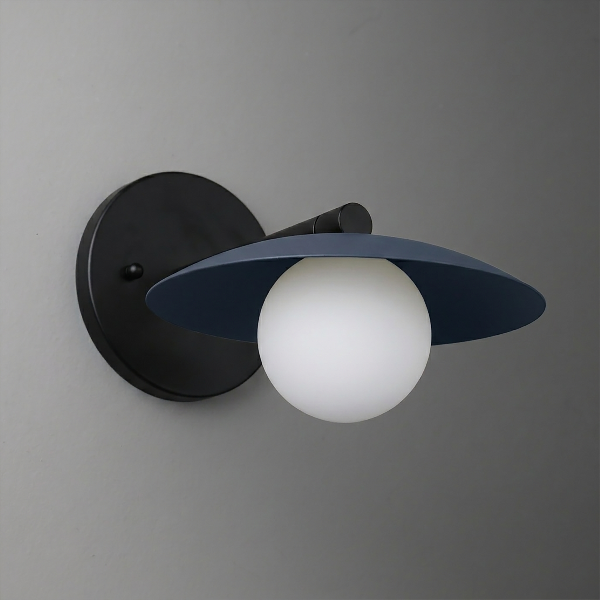 Black metal wall sconce with wide, flat circular shade and frosted globe bulb. - SCONCE MODEL NO. 9872