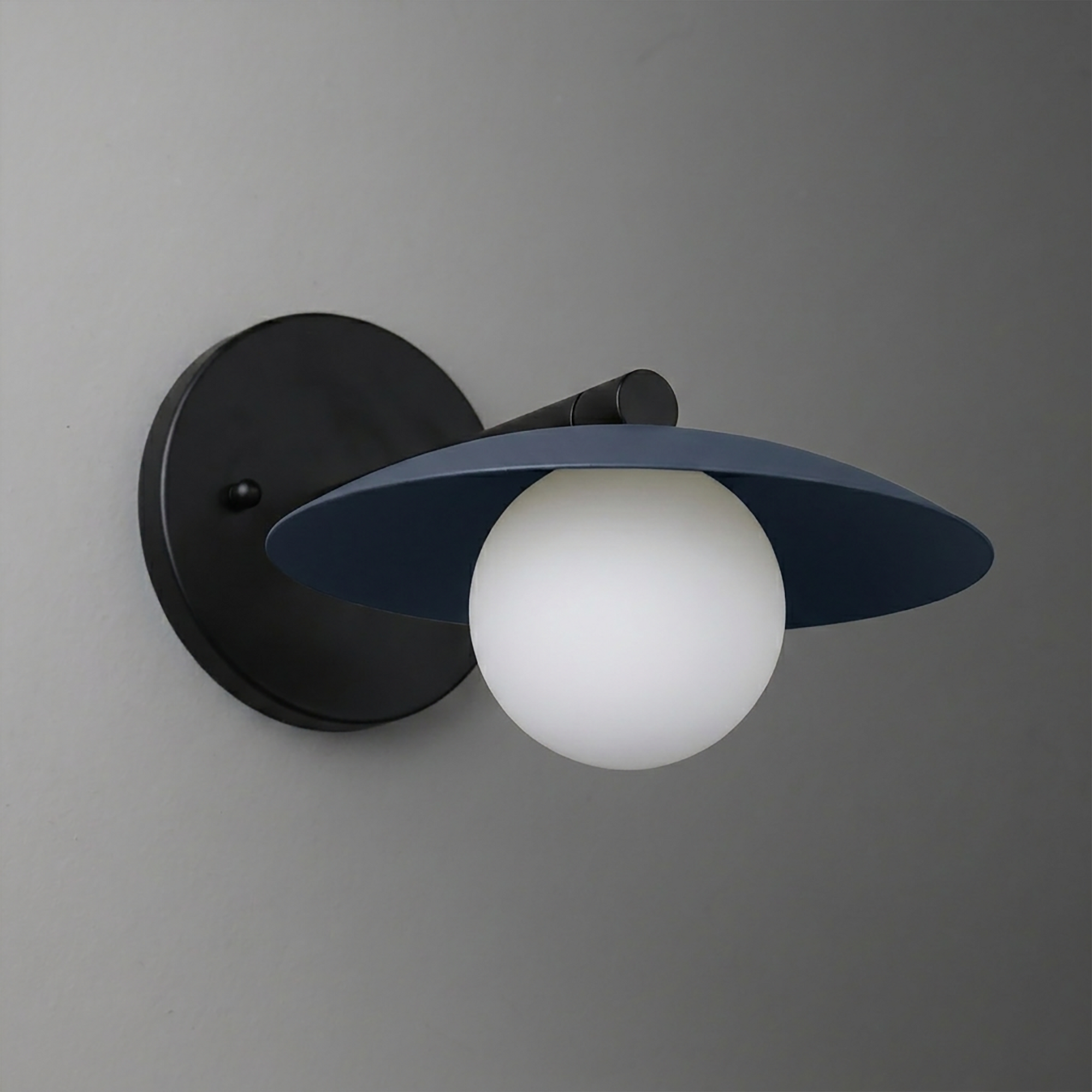 Black metal wall sconce with wide, flat circular shade and frosted globe bulb. - SCONCE MODEL NO. 9872