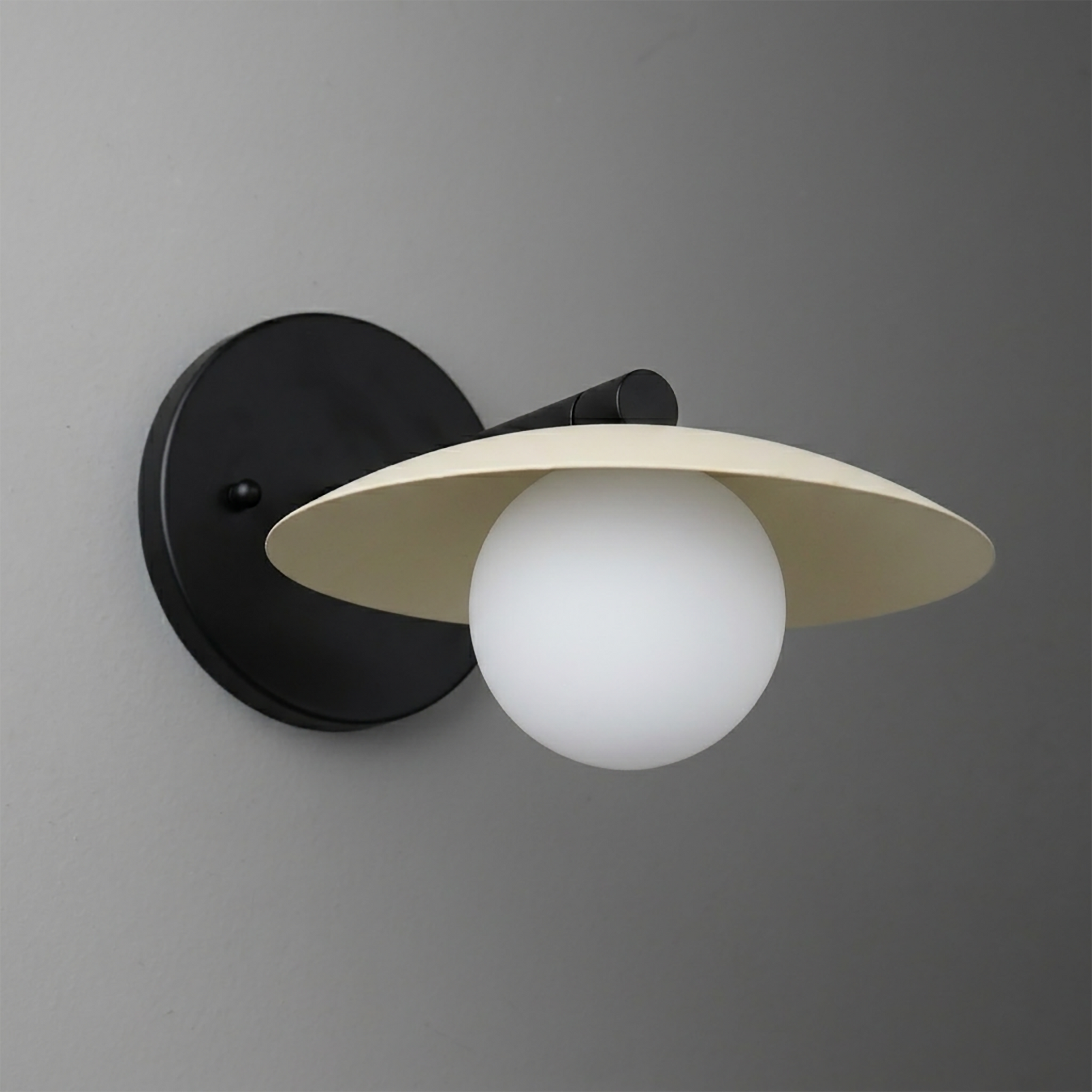 Matte black metal wall sconce with a wide cream-colored conical shade and a frosted white globe bulb beneath. - SCONCE MODEL NO. 9872