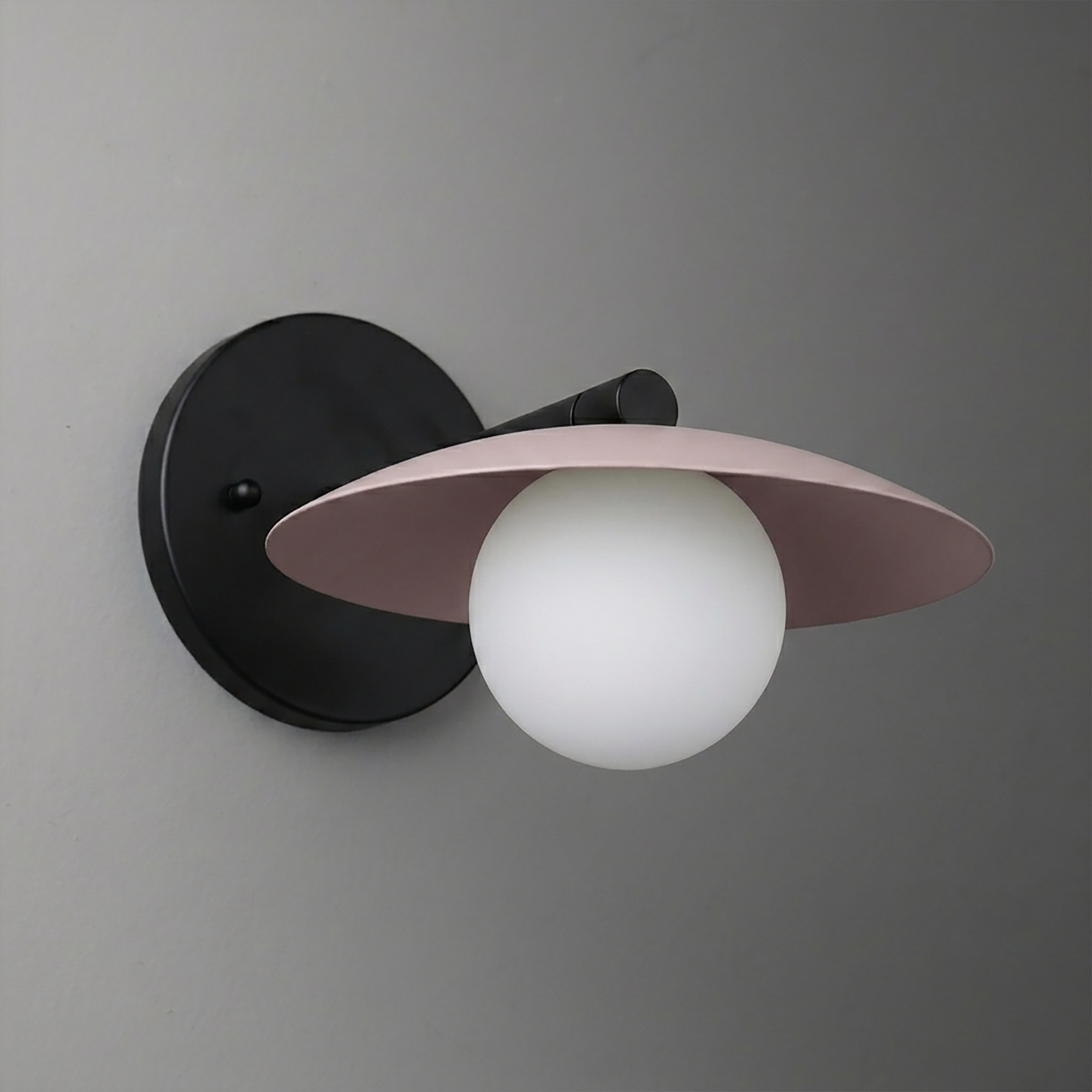 Black metal wall sconce with round backplate, white globe bulb, and wide mauve shade. - SCONCE MODEL NO. 9872