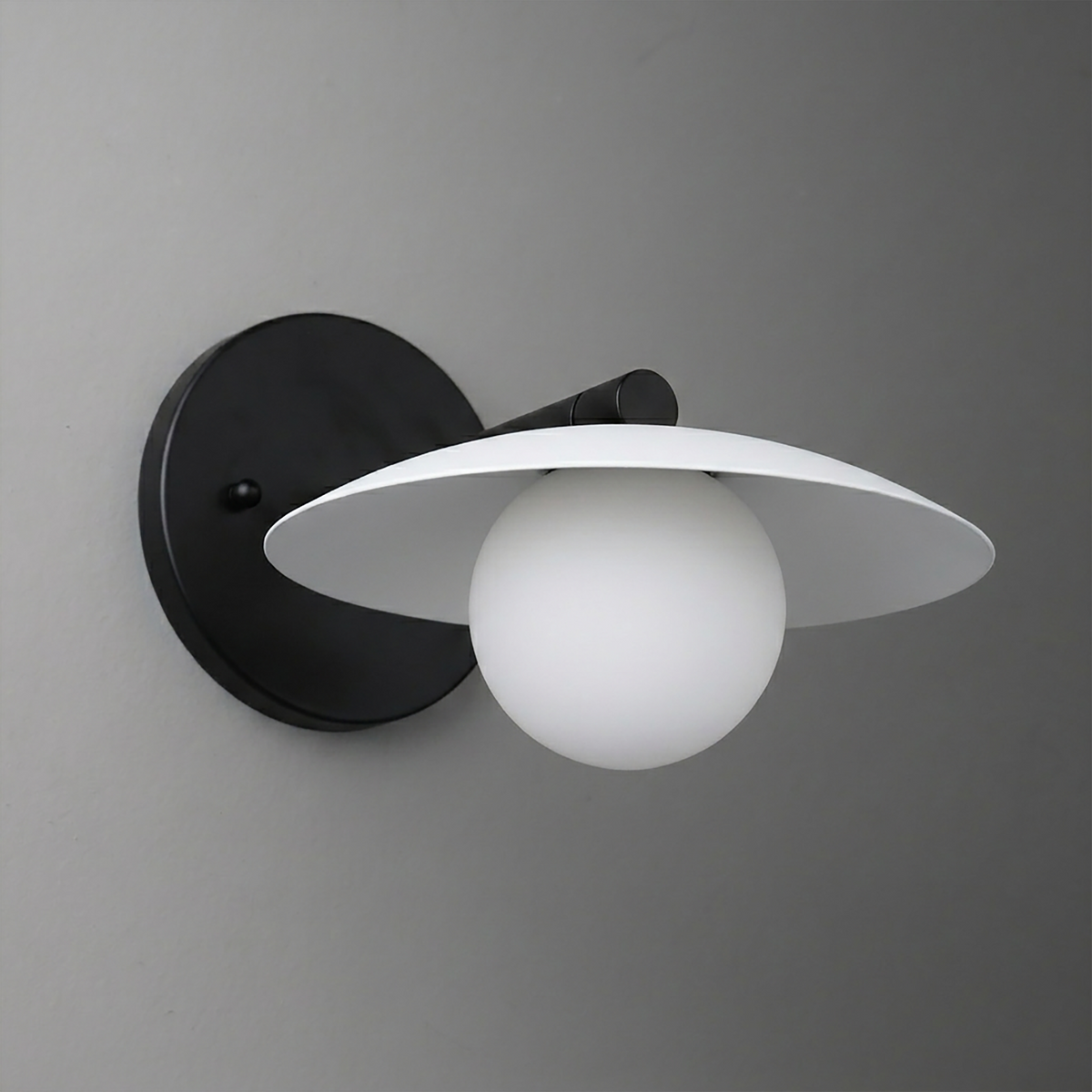 Black metal wall sconce with a white globe bulb and flat circular shade. - SCONCE MODEL NO. 9872