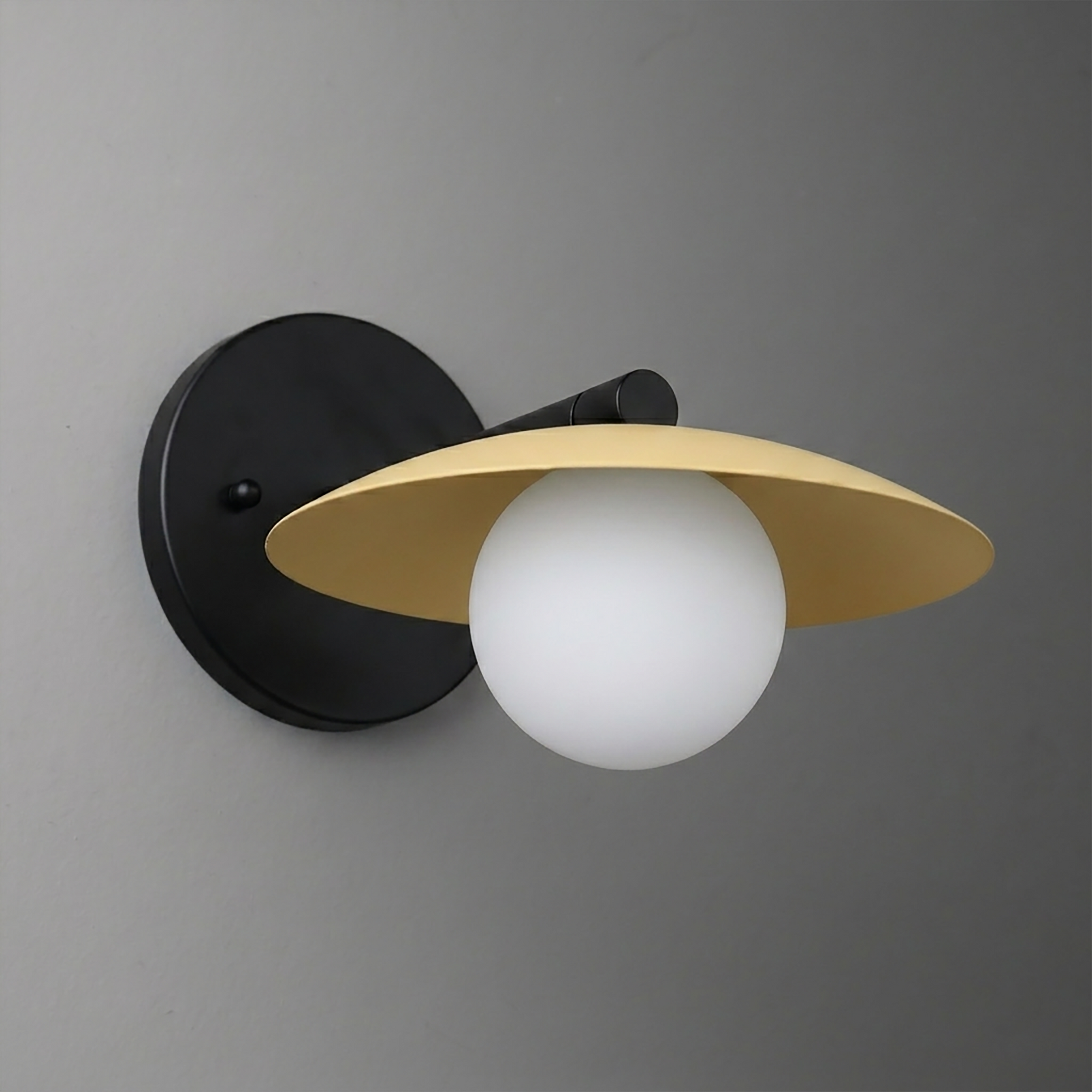 Wall sconce with matte black round base, angled brass-finished metal shade, and frosted white globe bulb. - SCONCE MODEL NO. 9872