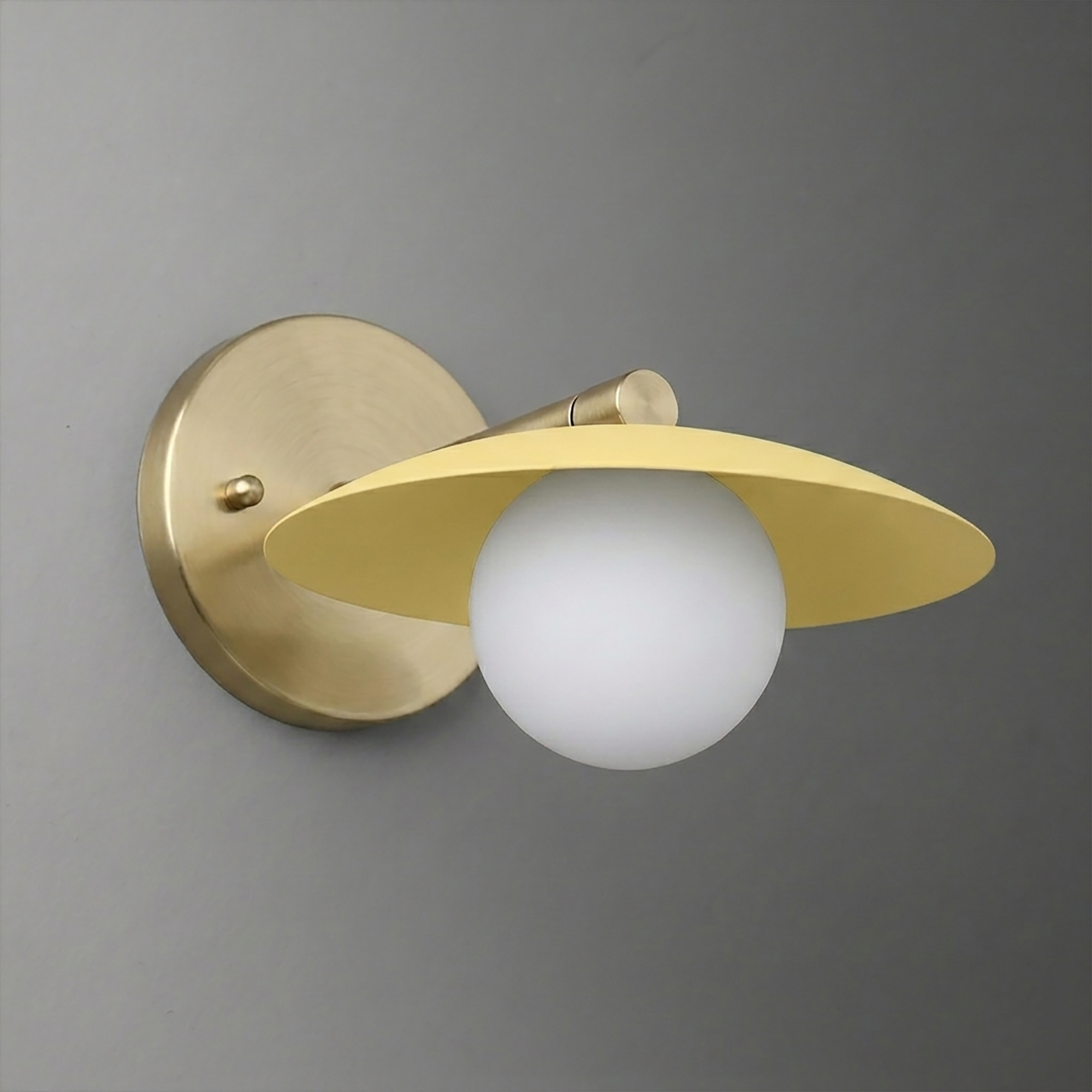 Brushed brass wall sconce with a round backplate and a matte yellow wide conical shade over a frosted white globe bulb. - SCONCE MODEL NO. 9872