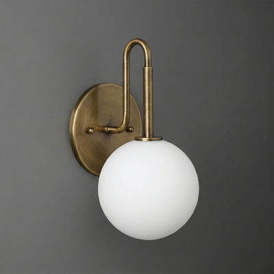 Wall-mounted sconce with a round brass base and arm holding a frosted white glass globe shade. - SCONCE MODEL NO. 9106