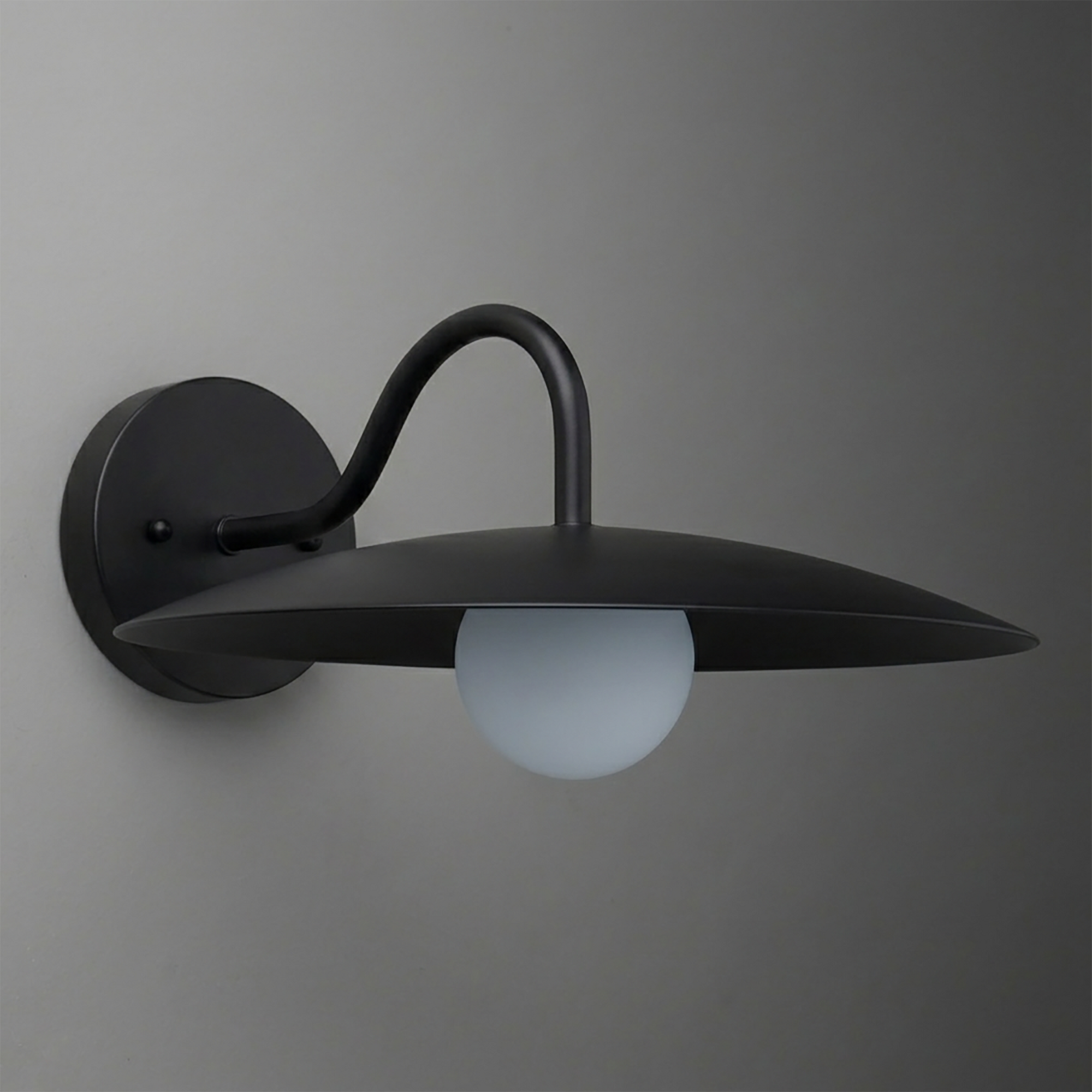 Black metal wall sconce with curved arm and wide, flat shade over frosted globe bulb. - SCONCE MODEL NO. 2162