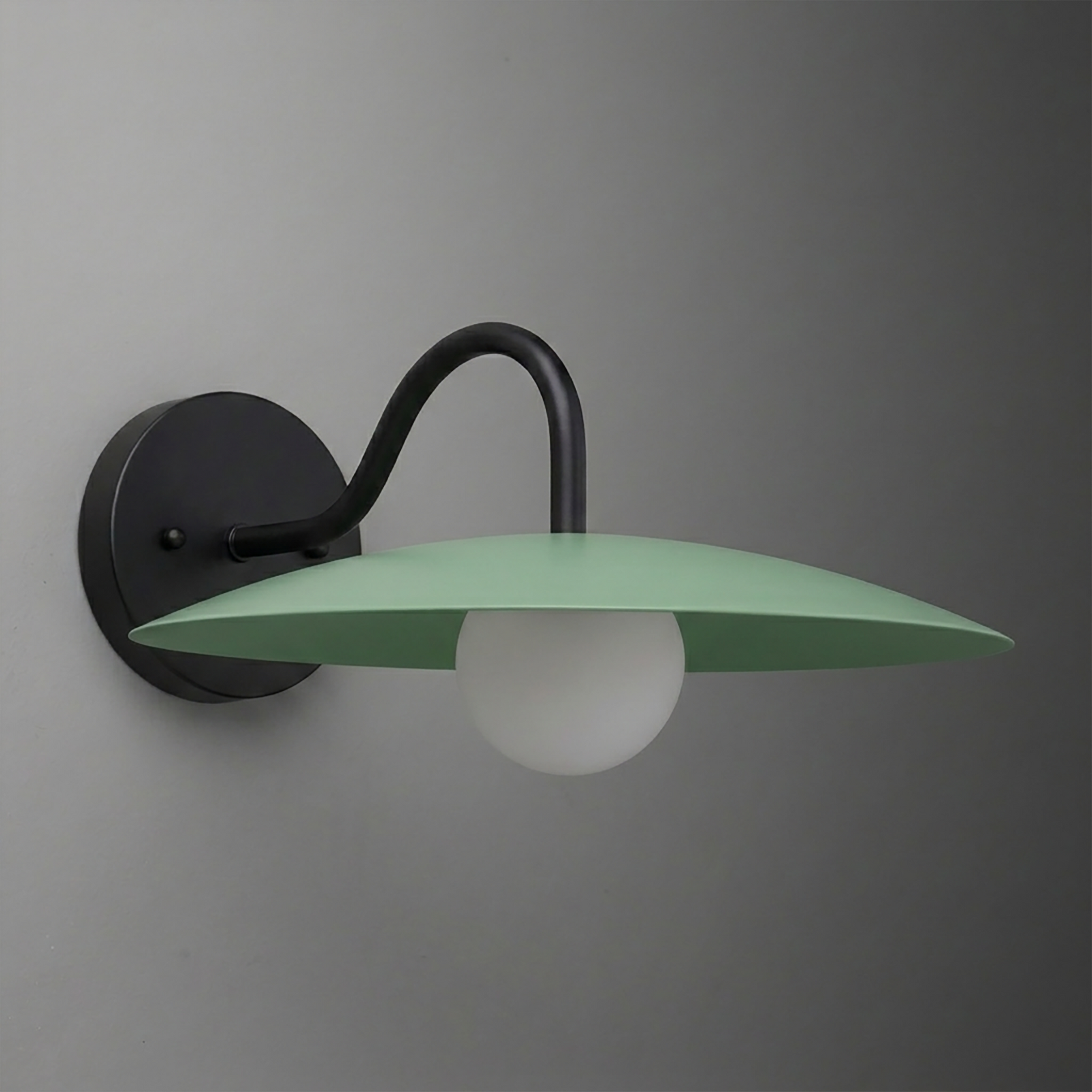 Matte black metal wall sconce with curved arm supporting a flat, wide green shade and a white globe bulb underneath. - SCONCE MODEL NO. 2162