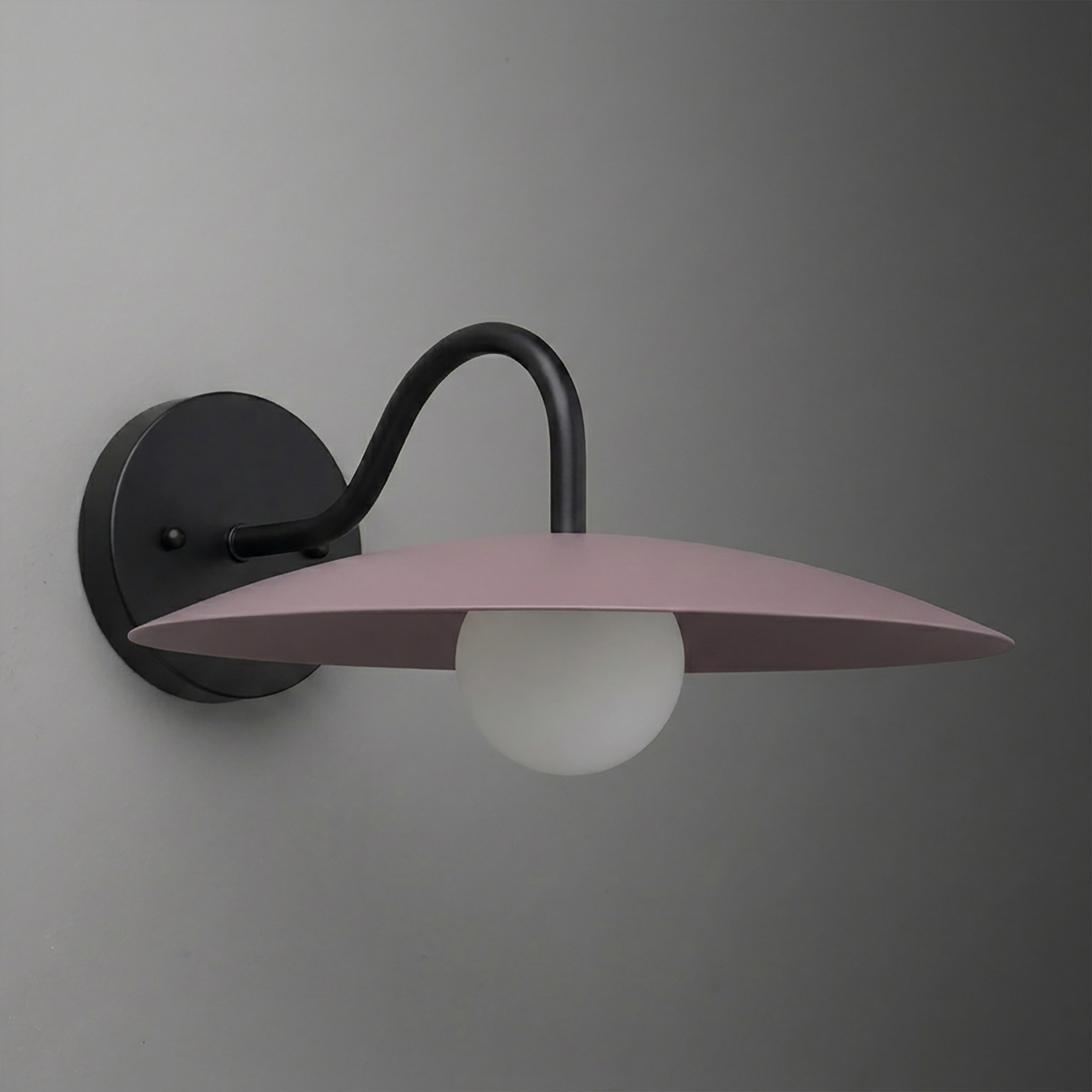 Matte black wall sconce with curved arm and wide flat mauve metal shade over round white bulb. - SCONCE MODEL NO. 2162