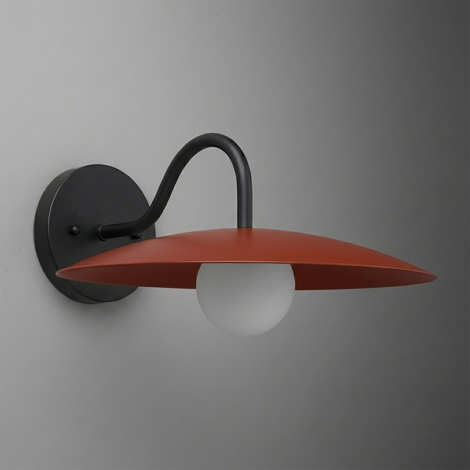 Wall sconce with matte black curved arm and round red-orange flat metal shade over frosted white bulb. - SCONCE MODEL NO. 2162