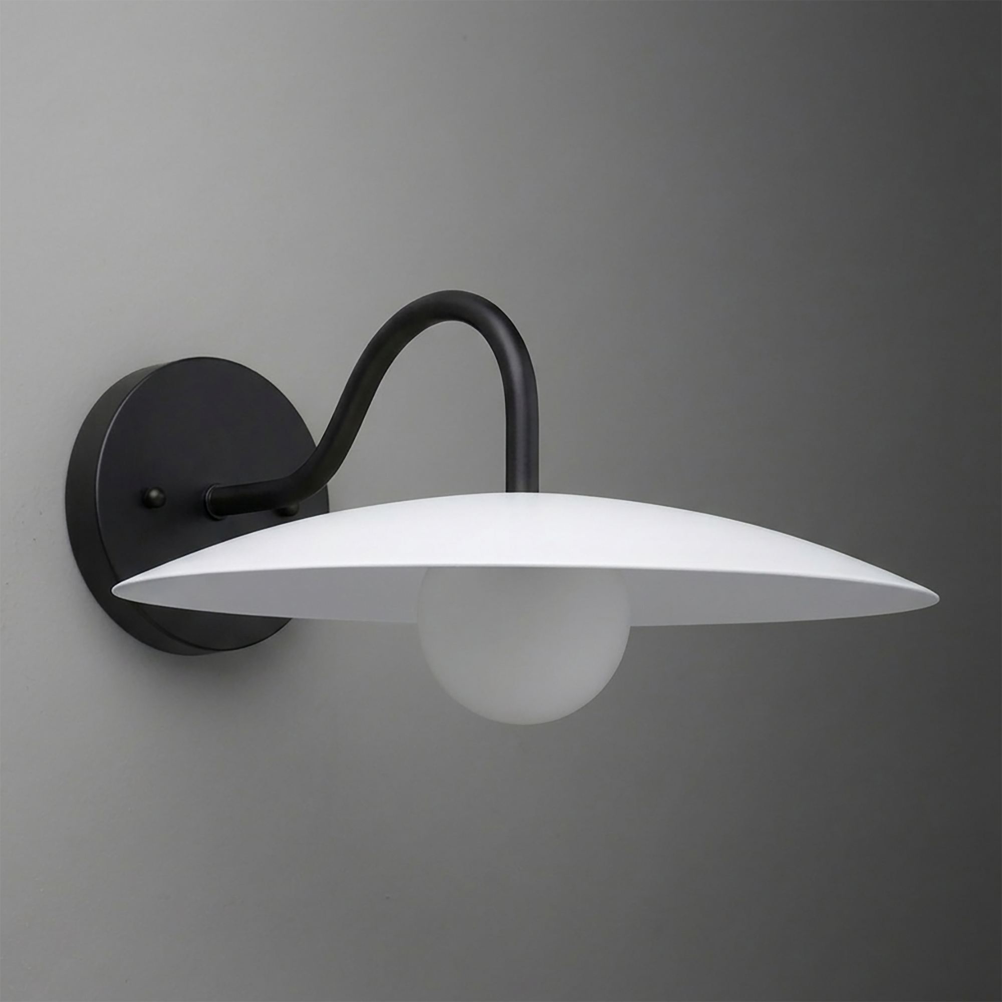 Matte black wall sconce with curved arm and flat, wide white glass shade over frosted globe bulb. - SCONCE MODEL NO. 2162