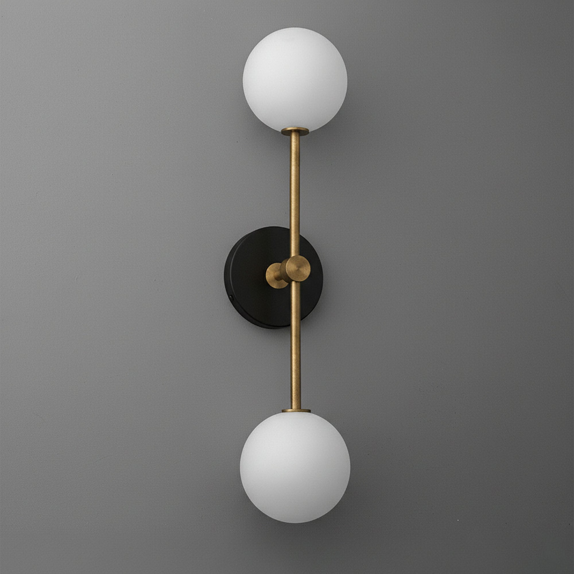 Modern double globe wall sconce with raw brass rod and black circular base. - SCONCE MODEL NO. 9776