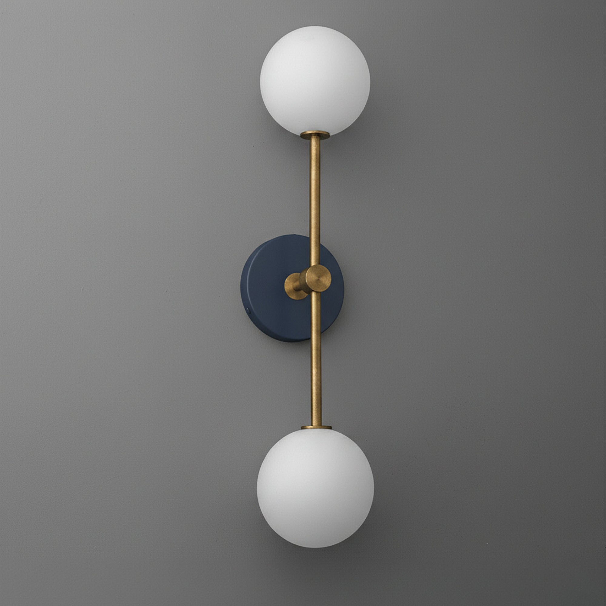 Raw brass and coal blue wall sconce with two white glass globe shades, vertical design. - SCONCE MODEL NO. 9776