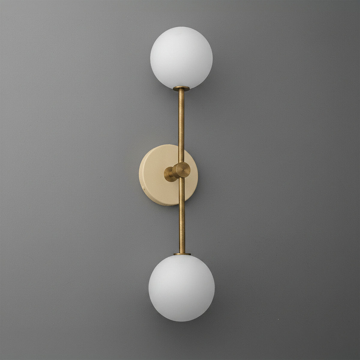 Wall sconce with raw brass finish and two round white frosted glass globes on vertical rod. - SCONCE MODEL NO. 9776
