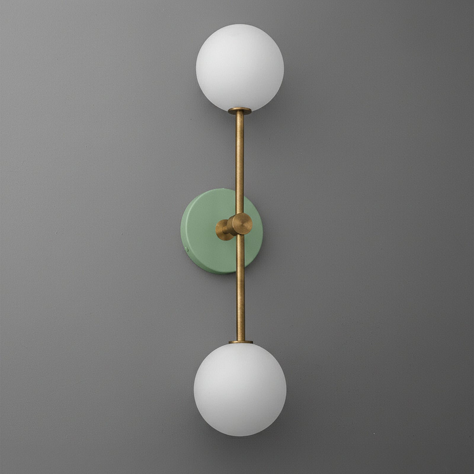 Modern raw brass double globe wall sconce with matte green circular backplate and frosted white glass shades. - SCONCE MODEL NO. 9776