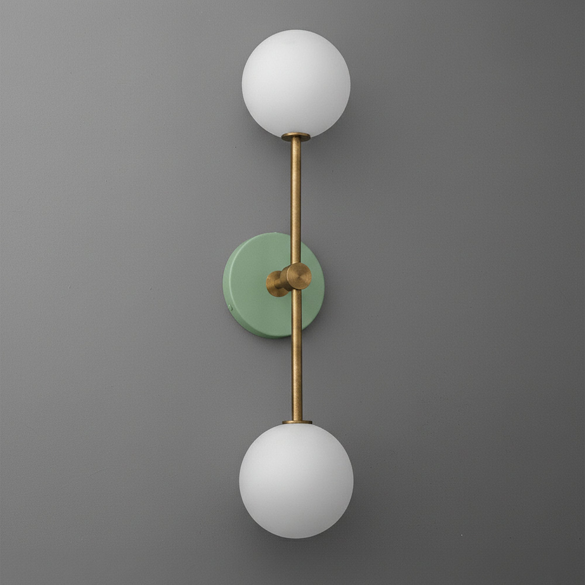 Modern raw brass double globe wall sconce with matte green circular backplate and frosted white glass shades. - SCONCE MODEL NO. 9776