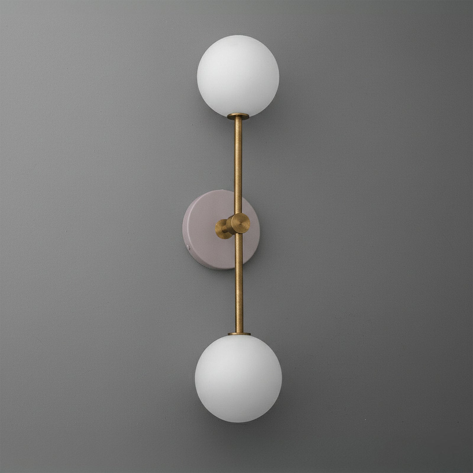Wall sconce with raw brass finish, mauve round base, and two white frosted glass globe shades. - SCONCE MODEL NO. 9776
