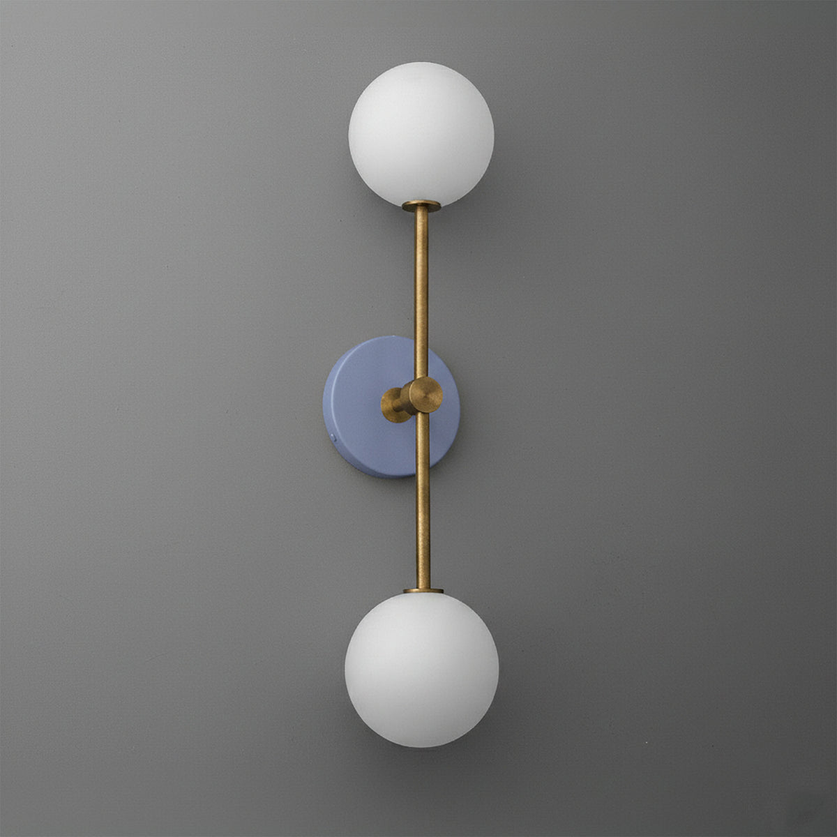 Wall sconce with raw brass finish and periwinkle circular backplate, featuring two white frosted glass globes. - SCONCE MODEL NO. 9776
