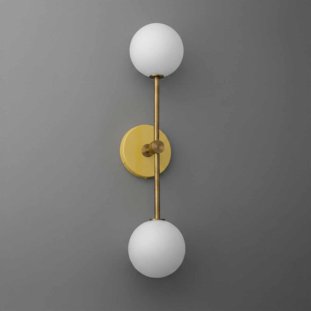 Raw brass double globe wall sconce with frosted white glass shades on gray background. - SCONCE MODEL NO. 9776