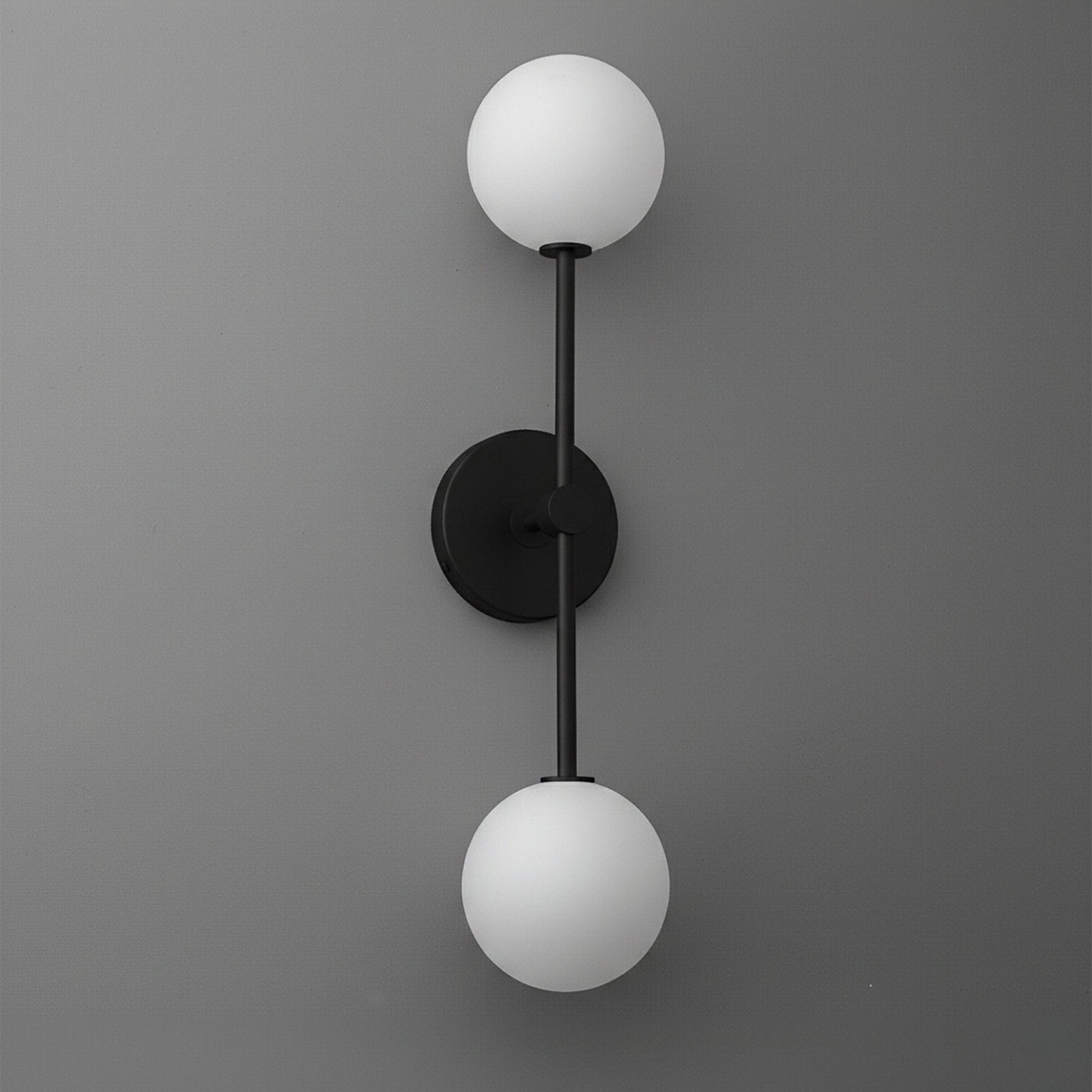 Black metal sconce with two frosted white glass globe shades on a gray wall. - SCONCE MODEL NO. 9776
