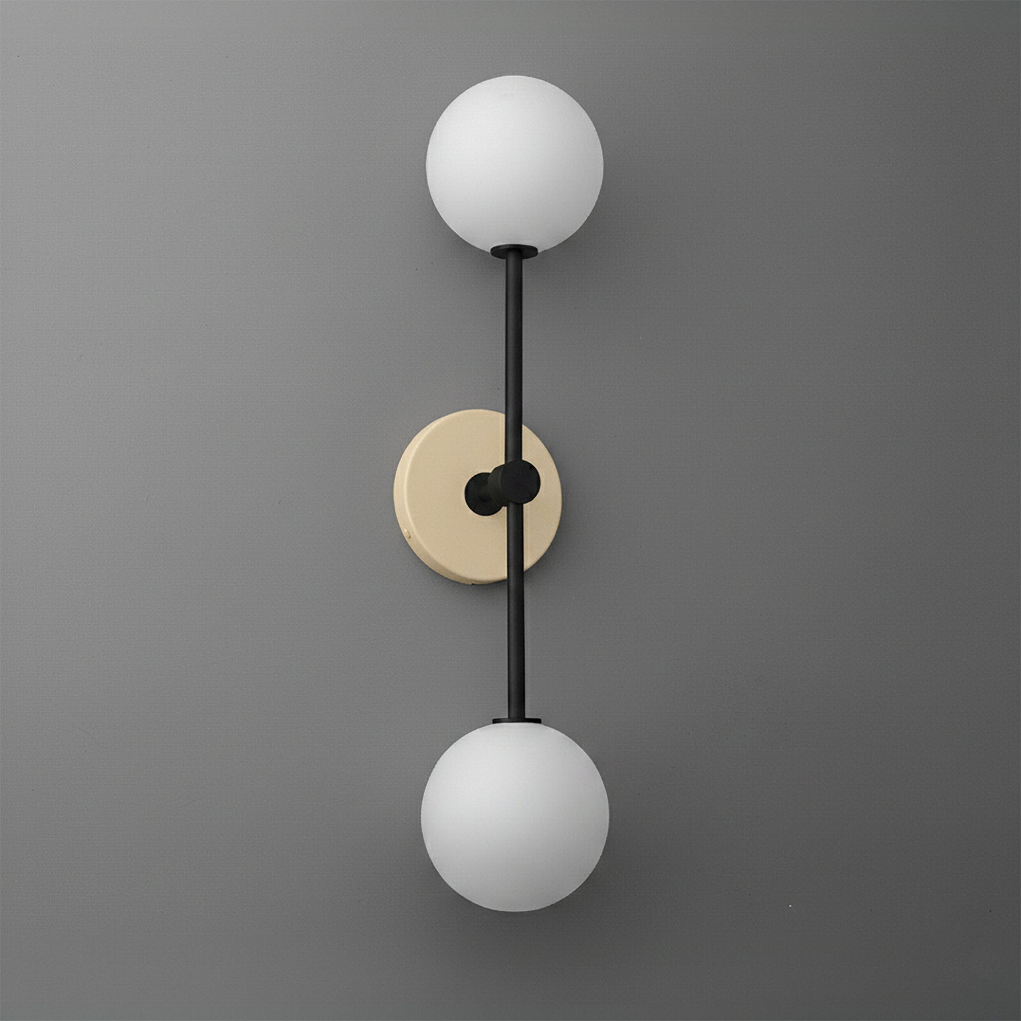 Double globe wall sconce with raw brass circular backplate and black vertical rod. - SCONCE MODEL NO. 9776