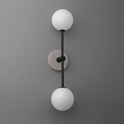Modern dual-globe wall sconce with matte black metal rod and mauve circular backplate on gray wall. - SCONCE MODEL NO. 9776