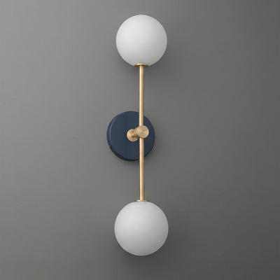 Wall sconce with raw brass finish, two frosted white glass globes, and a dark blue circular backplate. - SCONCE MODEL NO. 9776