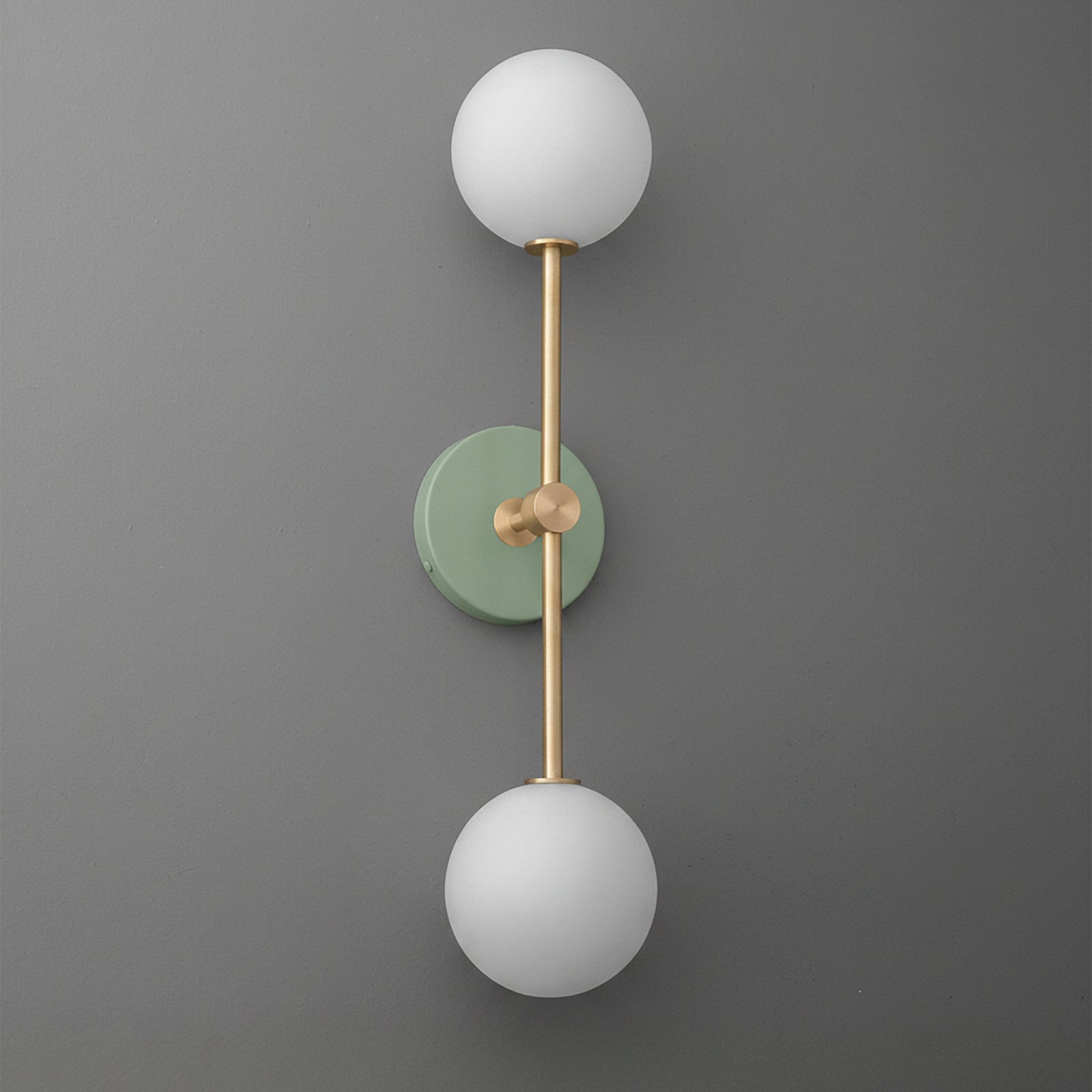 Raw brass wall sconce with two frosted white glass globes and a matte green circular base. - SCONCE MODEL NO. 9776