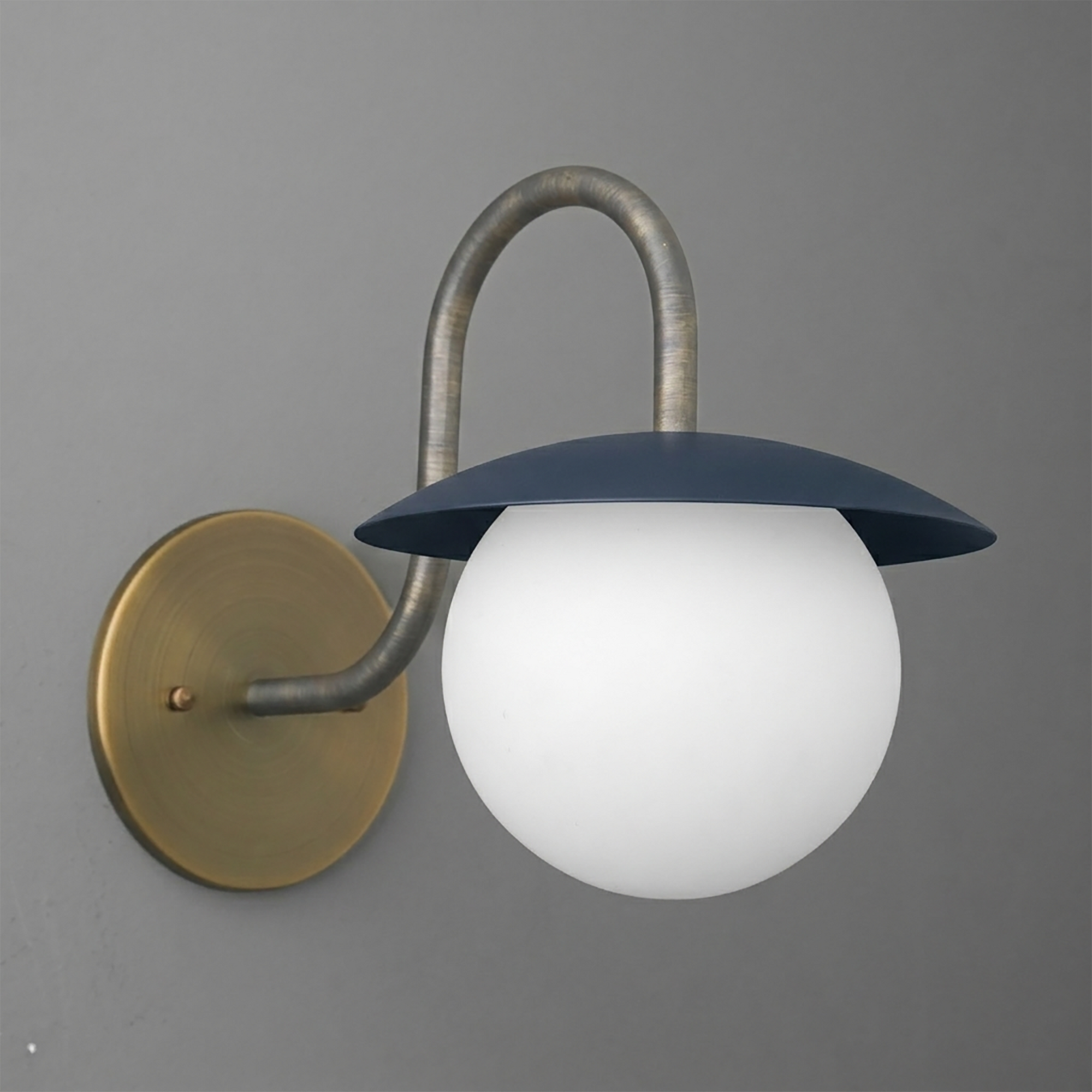Wall sconce with a round brass base, curved metal arm, and navy blue metal shade over a frosted white glass globe bulb. - SCONCE MODEL NO. 2206