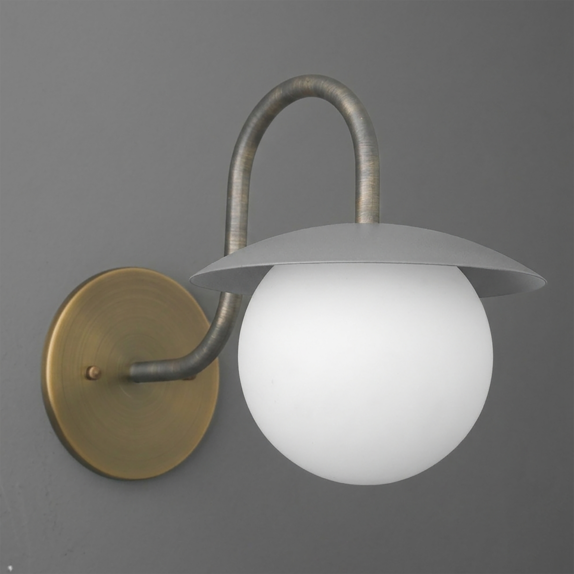 Wall-mounted sconce with round frosted glass globe and curved metal arm in antique brass and gray finish. - SCONCE MODEL NO. 2206
