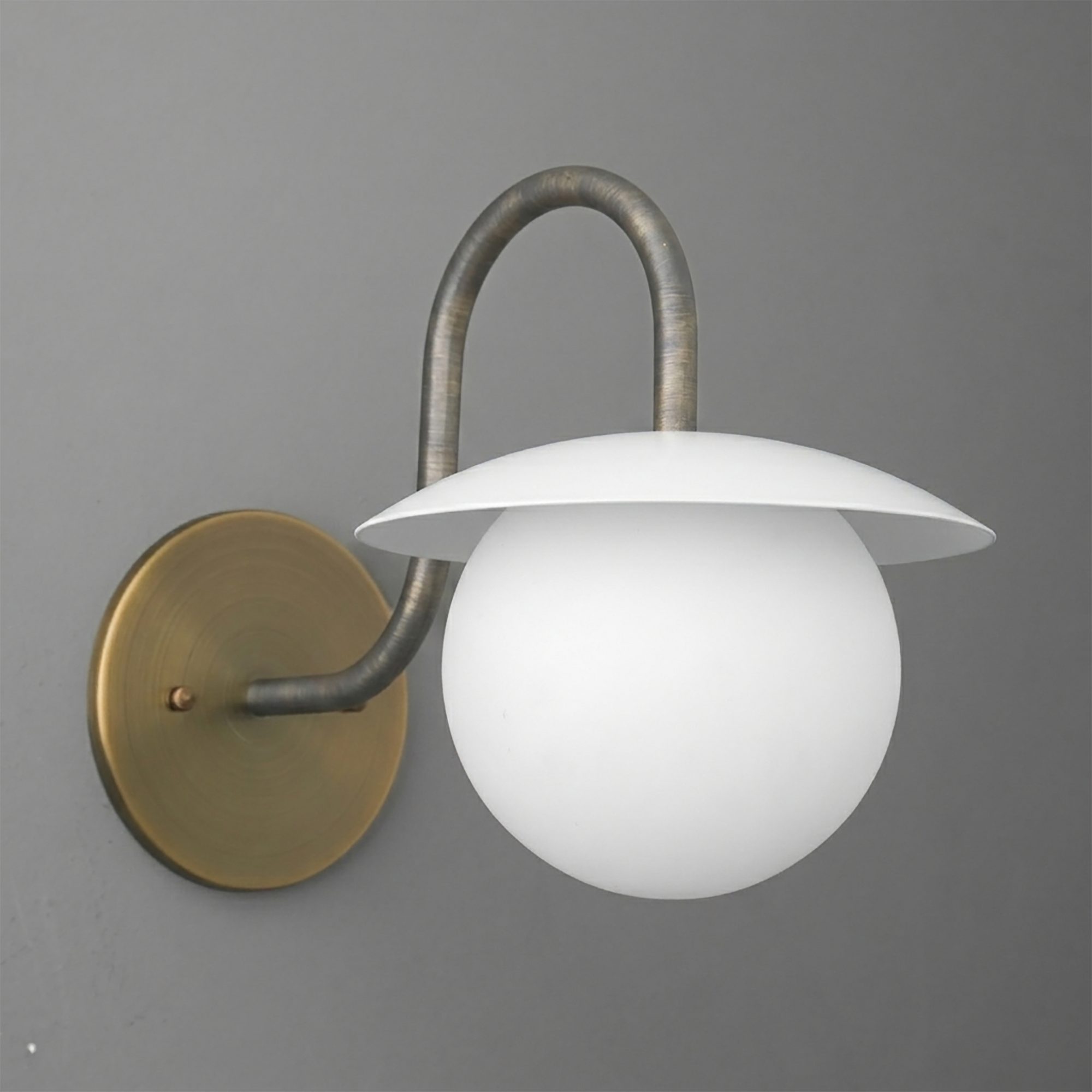 Wall-mounted sconce with round brass base, curved dark metal arm, and white glass globe shade topped by a flat white metal. - SCONCE MODEL NO. 2206