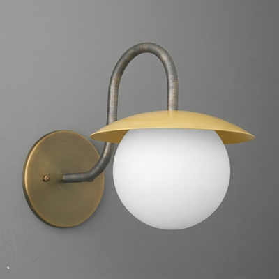 Wall sconce with aged brass finish, curved arm, flat yellow metal shade, and white frosted glass globe bulb cover. - SCONCE MODEL NO. 2206