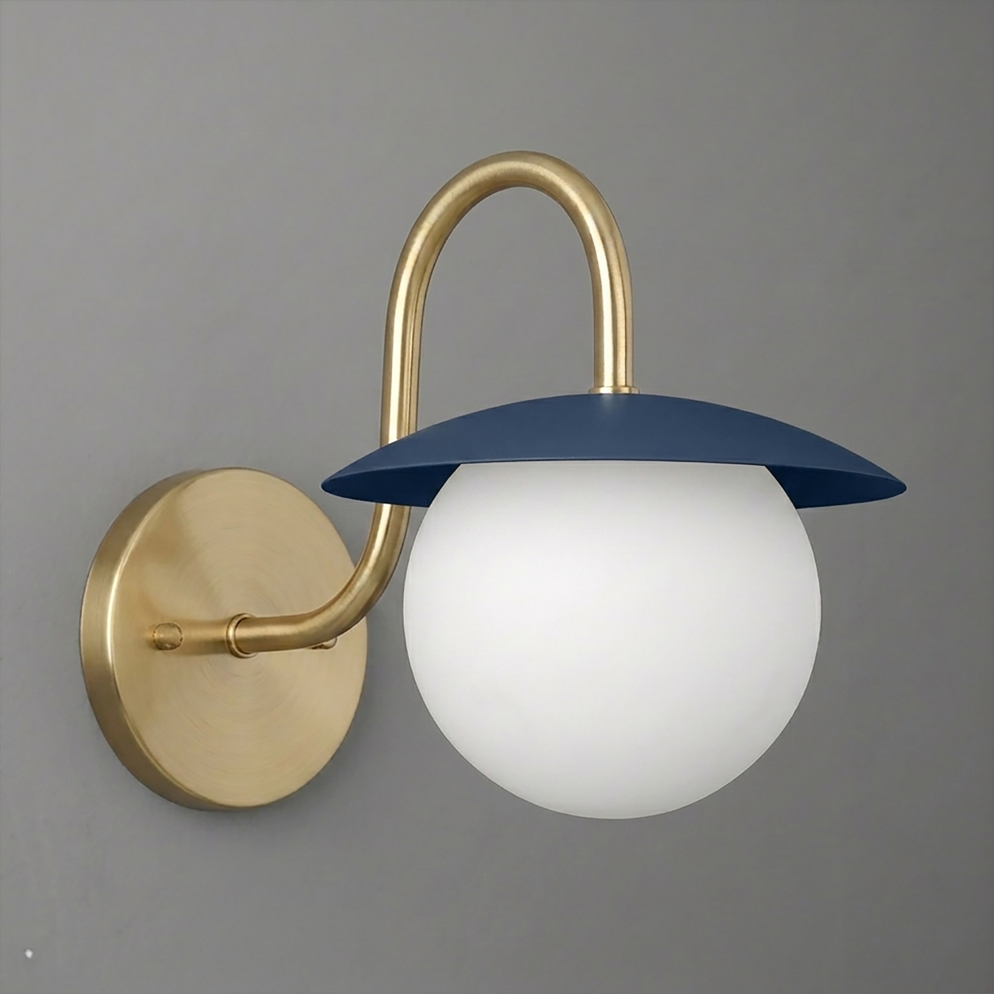 Wall sconce with brushed brass curved arm and round matte blue metal shade over white frosted glass globe light bulb cover. - SCONCE MODEL NO. 2206
