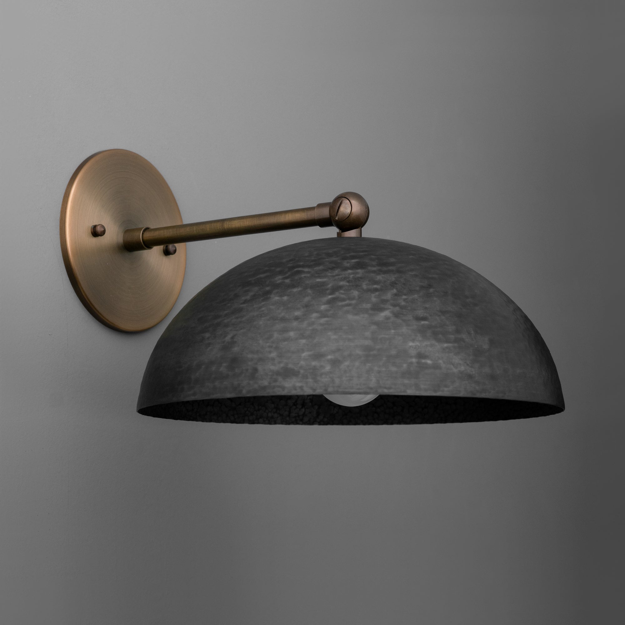 Wall sconce with matte black domed shade and antique brass arm and mounting plate against gray background. - SCONCE MODEL NO. 3164