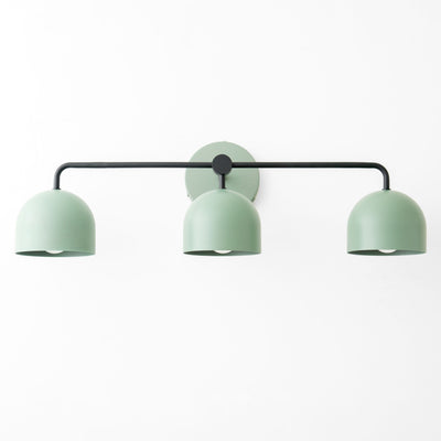 Mid-century modern triple vanity light with matte black horizontal bar and soft green dome-shaped shades. - VANITY LIGHT MODEL NO. 7456