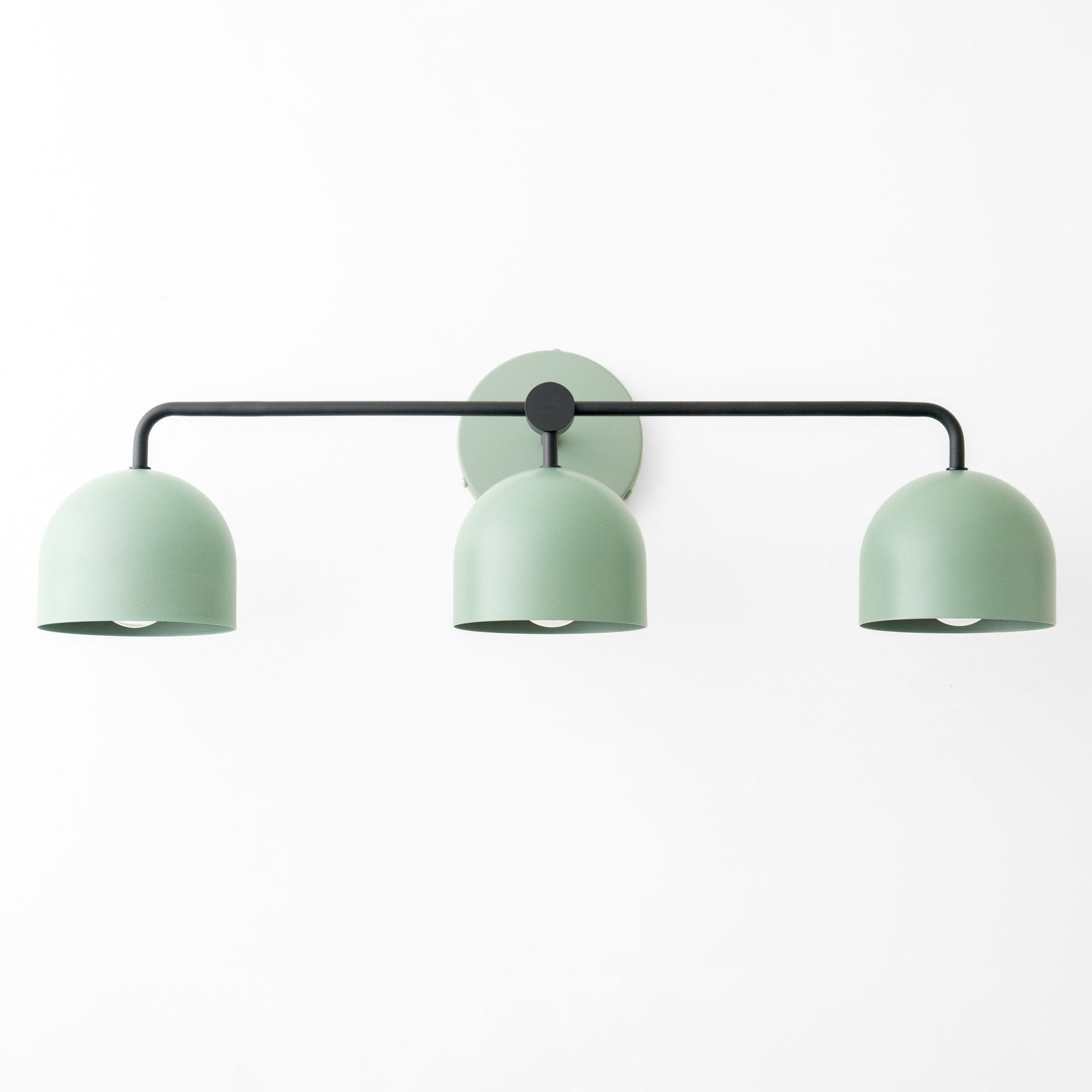 Matte sage green vanity light with three dome-shaped metal shades and black horizontal bar. - VANITY LIGHT MODEL NO. 7456