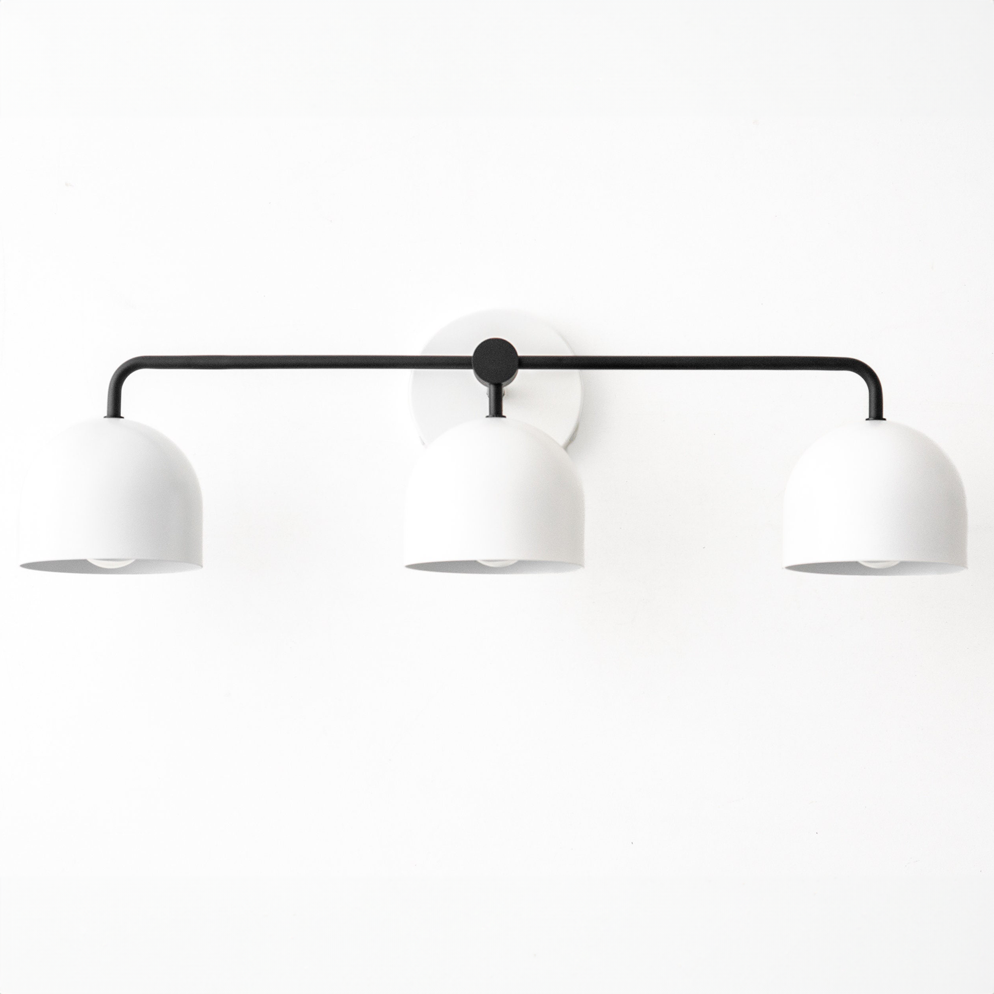 Three-bulb vanity light with black horizontal bar and white dome shades in mid-century modern style. - VANITY LIGHT MODEL NO. 7456