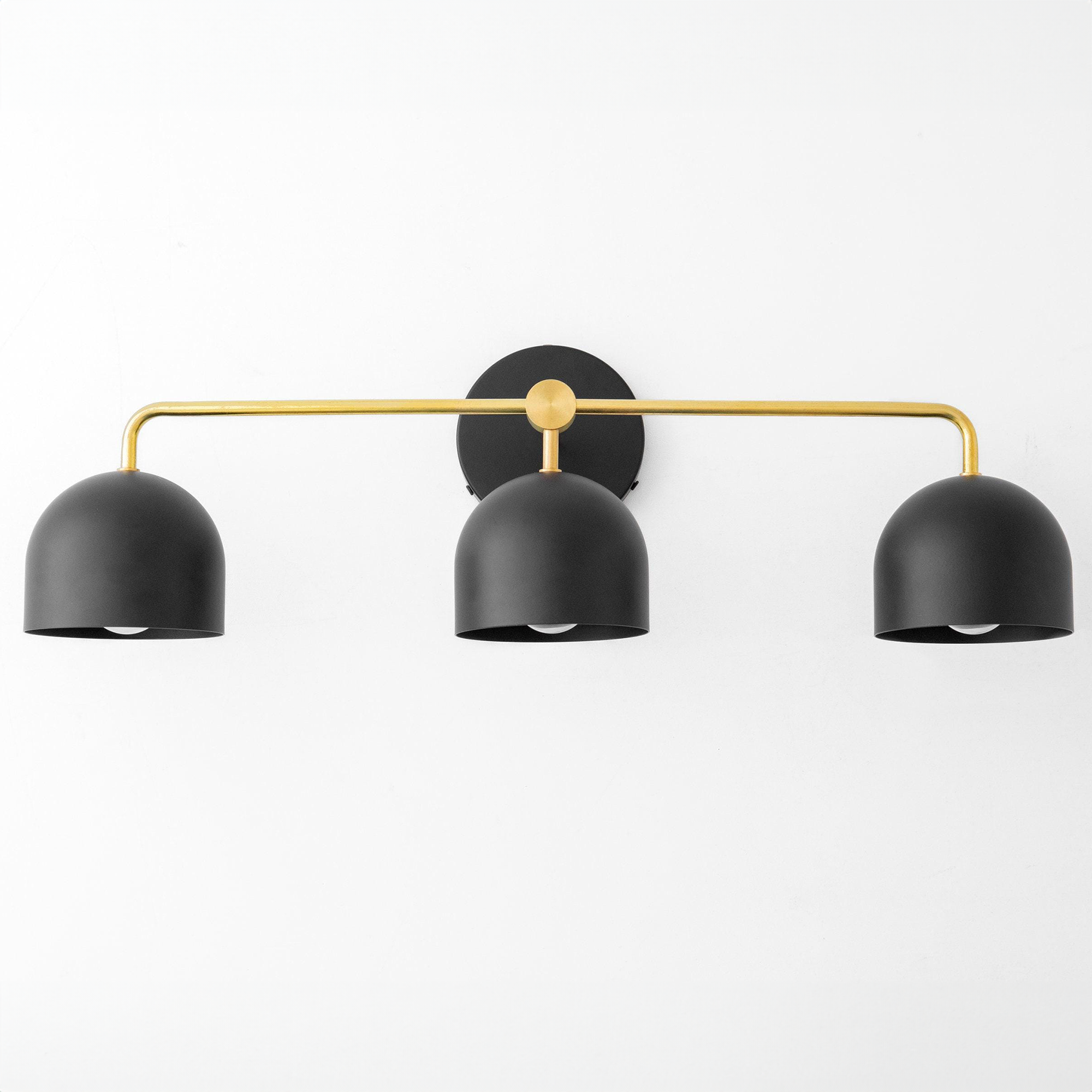 Mid-century modern vanity light with three matte black dome shades and a curved brass arm. - VANITY LIGHT MODEL NO. 7456