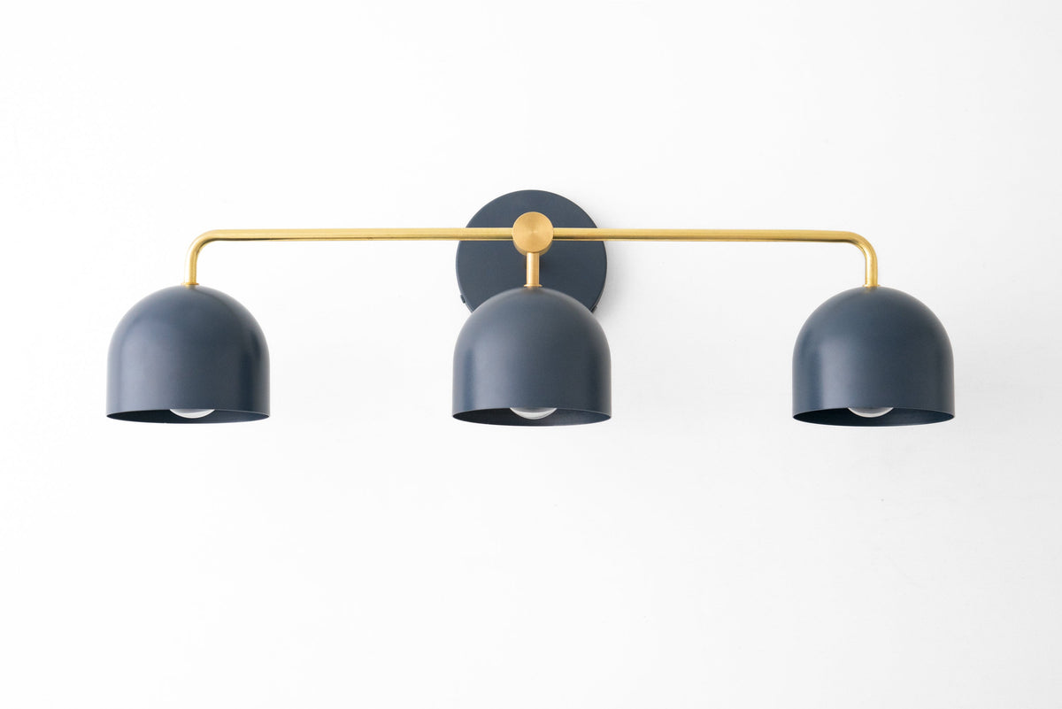 Deep blue three-bulb vanity light with curved shades and a slim gold horizontal bar mounting on a round black base. - VANITY LIGHT MODEL NO. 7456