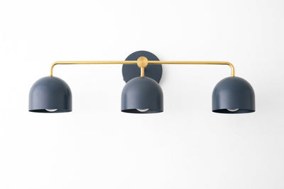 Deep blue three-bulb vanity light with curved shades and a slim gold horizontal bar mounting on a round black base. - VANITY LIGHT MODEL NO. 7456