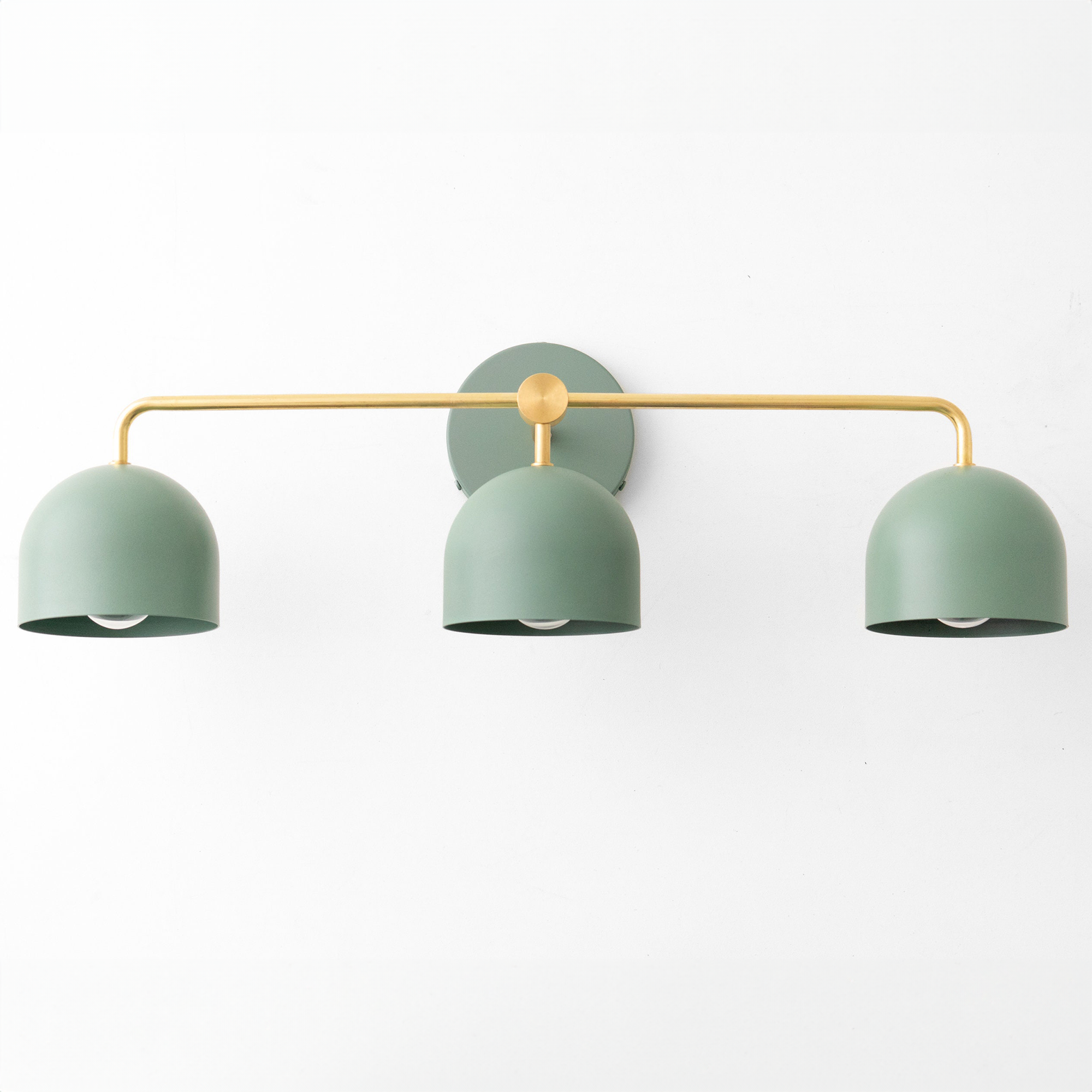 Mid-century modern vanity light with three matte sage green dome shades and brass horizontal bar mount. - VANITY LIGHT MODEL NO. 7456