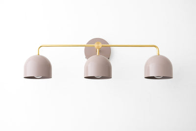 Three-bulb vanity light with matte beige dome shades and gold metal fixture in mid-century modern style. - VANITY LIGHT MODEL NO. 7456