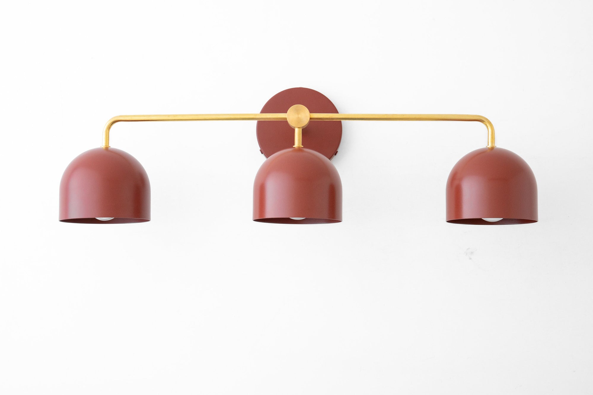 Mid-century modern vanity light with three deep red dome shades and a brass horizontal bar mount. - VANITY LIGHT MODEL NO. 7456