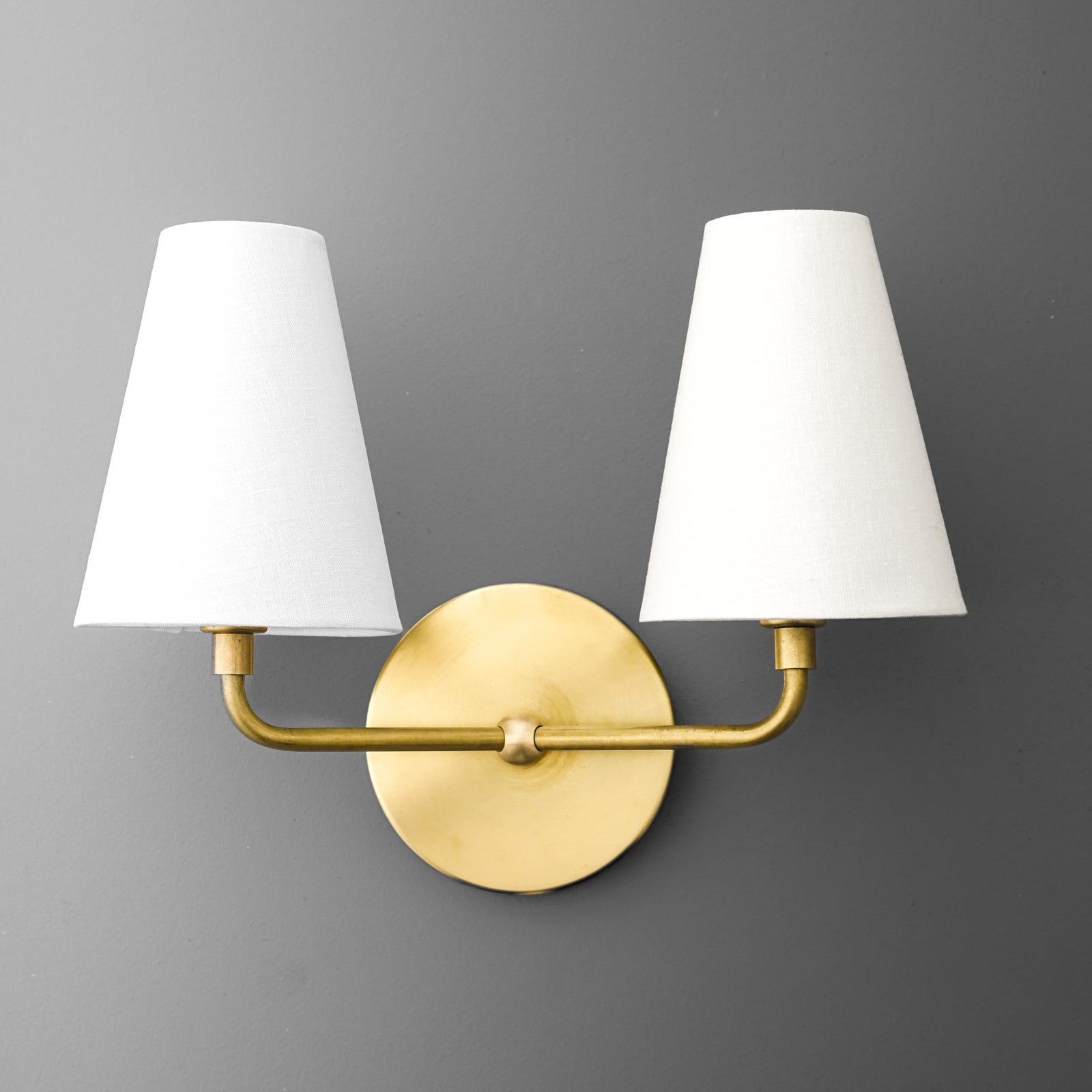 Brushed brass two-bulb wall sconce with white fabric tapered shades on a round backplate. - SCONCE MODEL NO. 0823