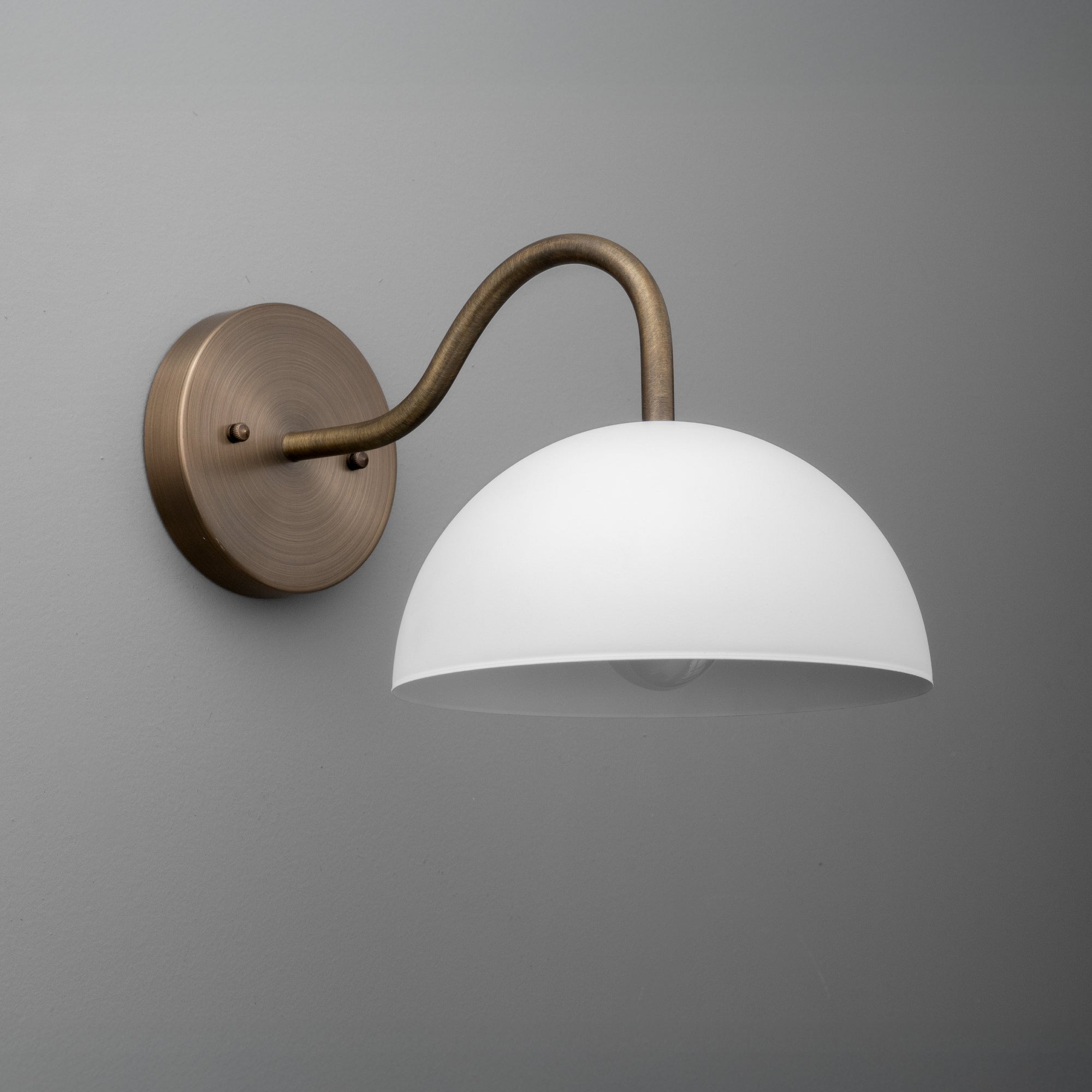Raw brass wall sconce with a smooth white glass dome shade and curved arm mount. - SCONCE MODEL NO. 6679