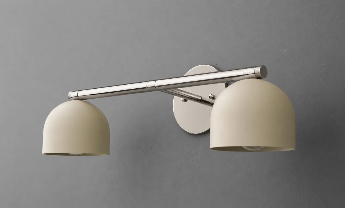 Angled view of the two-light vanity light in Polished Nickel with Cream steel dome shades on a straight bar and round wall plate. - VANITY LIGHT MODEL NO. 1186