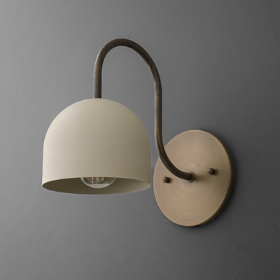 Matte cream dome-shaped metal sconce with curved dark brass arm and round wall plate against gray background. - SCONCE MODEL NO. 6308